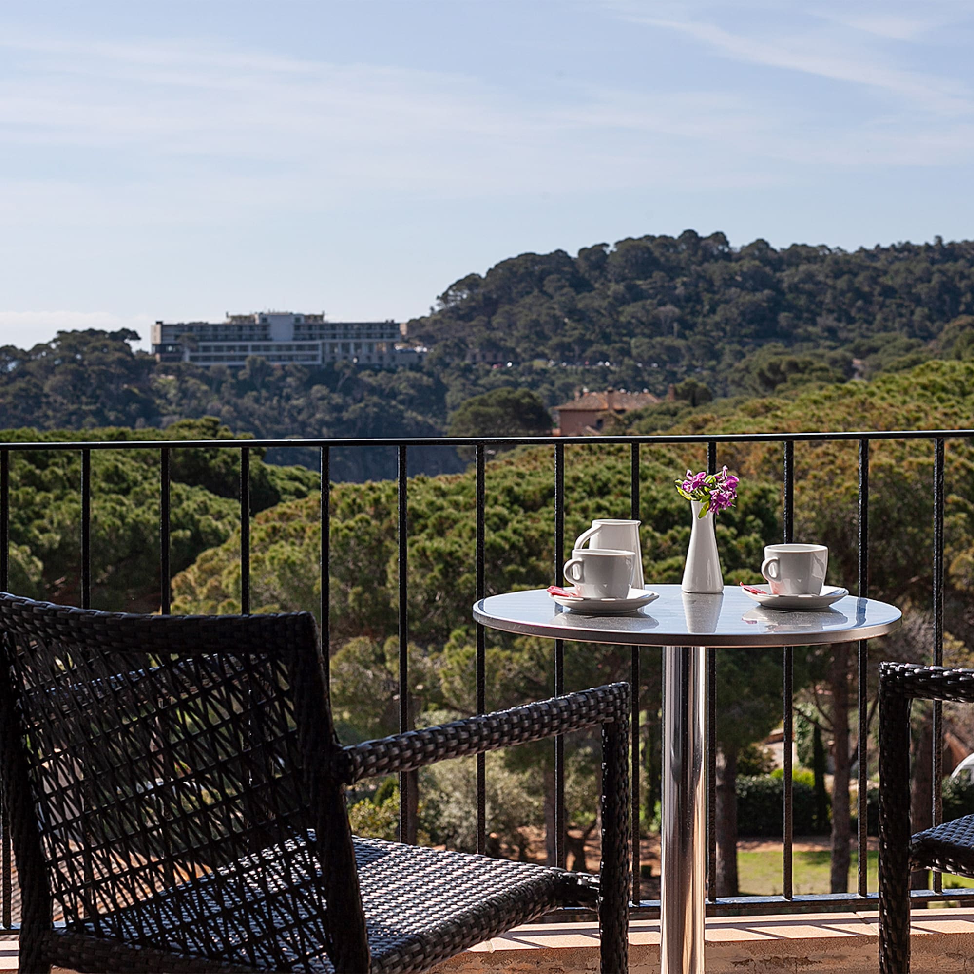 a table and chairs on a balcony overlooking trees and a city