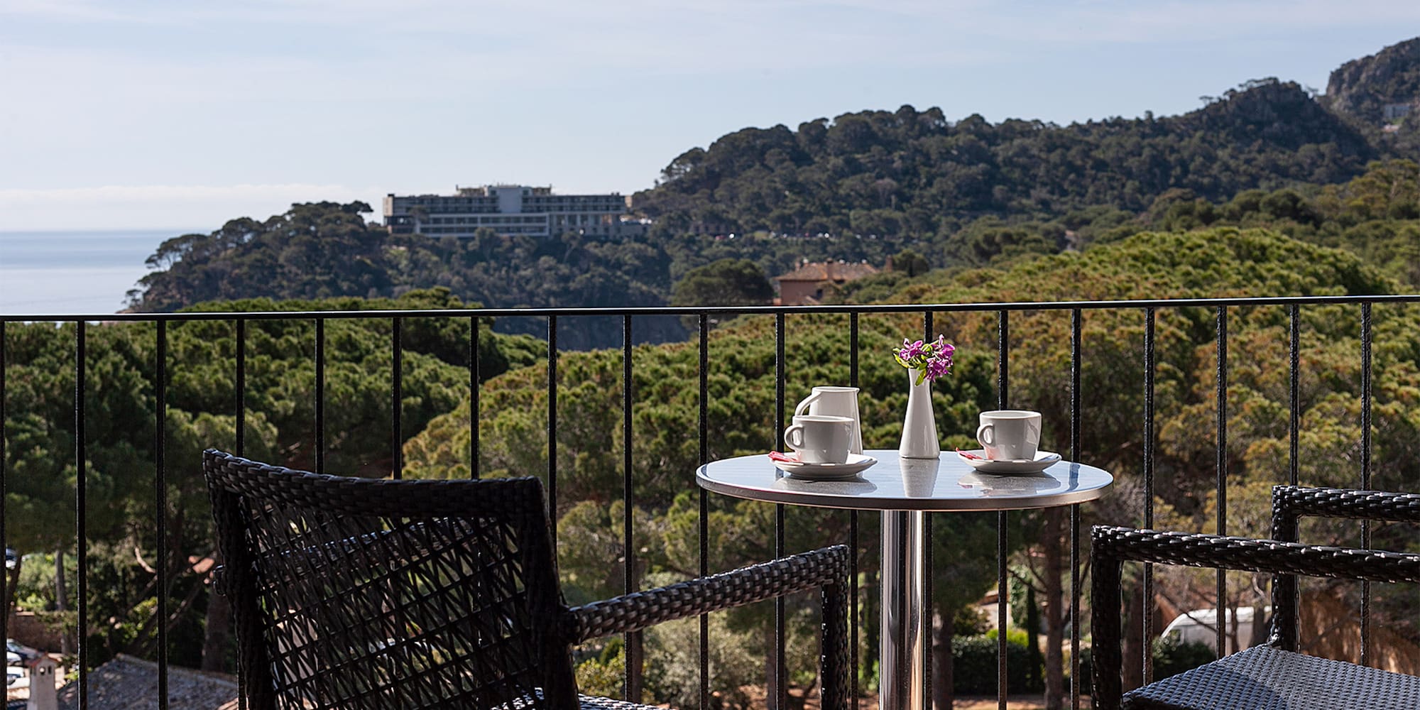 a table and chairs on a balcony overlooking trees and a city