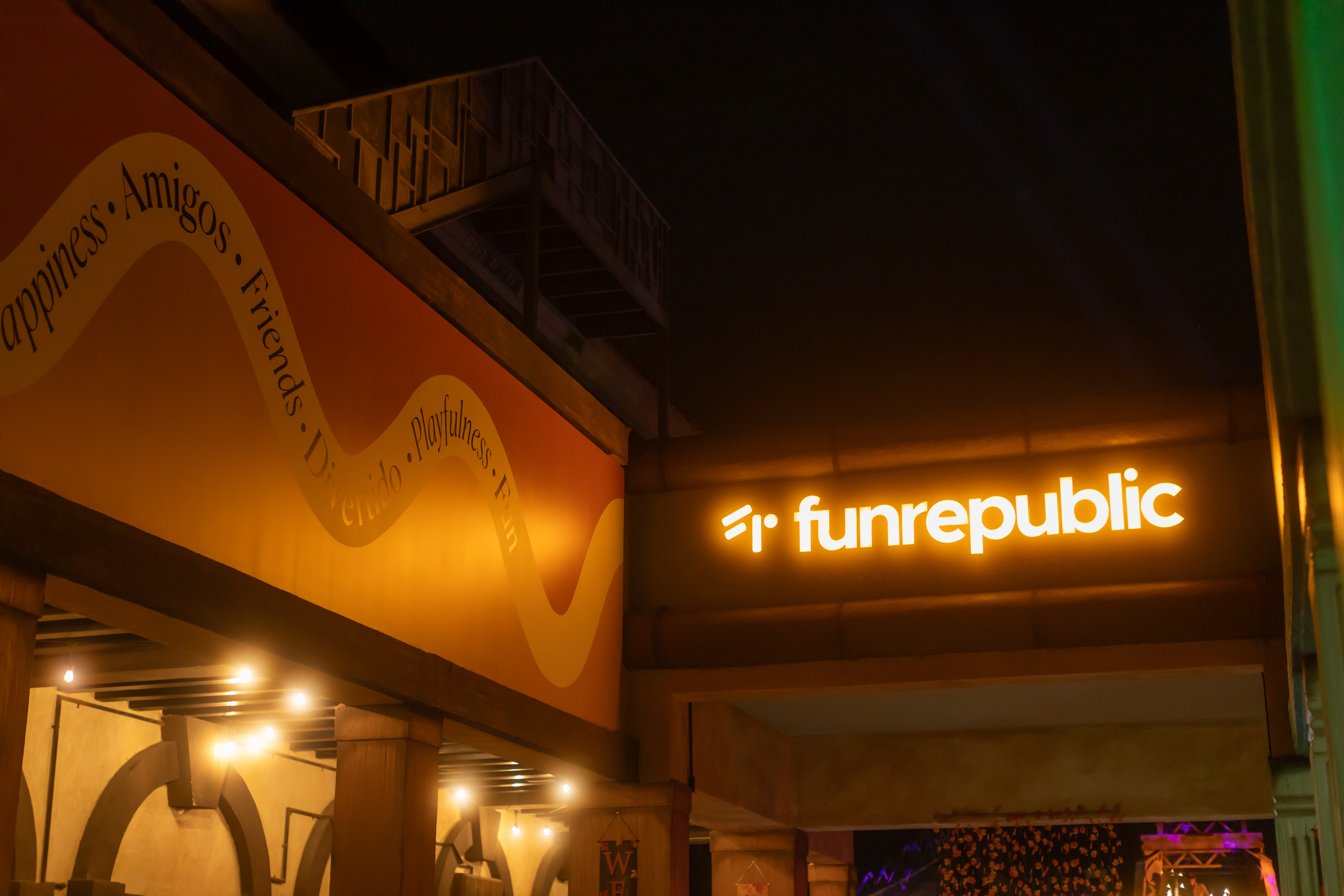 Illuminated Funrepublic sign, with 'Happiness, Amigos' wall text.