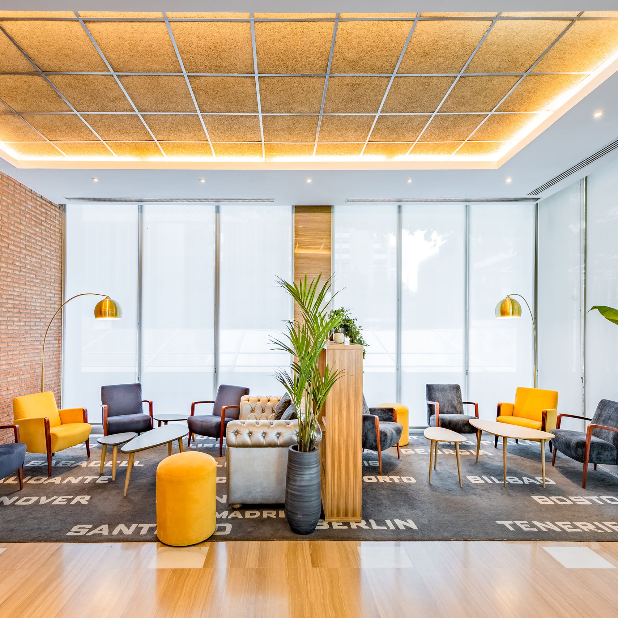 Contemporary hotel lobby with colorful seating, brick wall, and bright windows.
