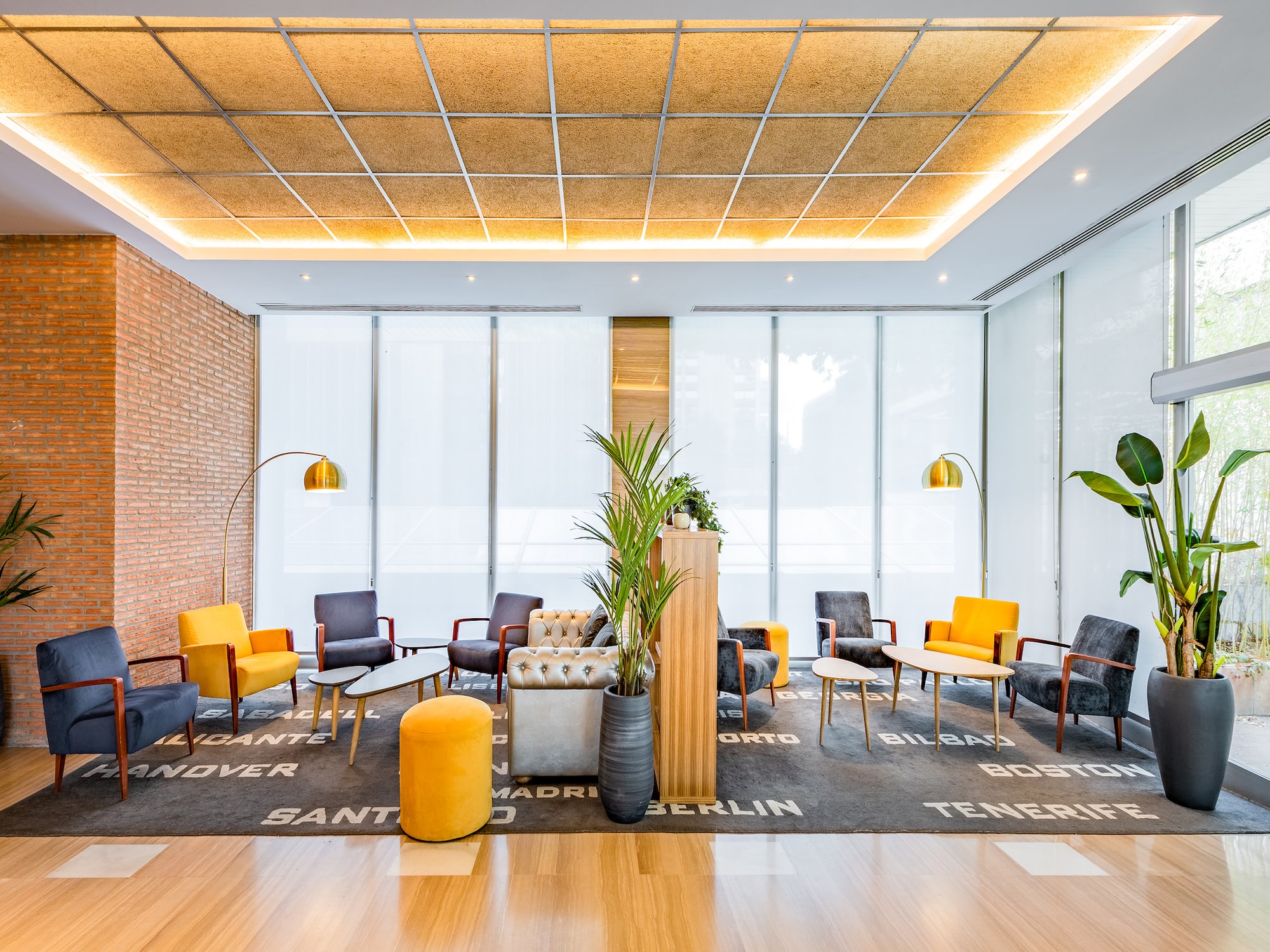 Vestíbulo hotel moderno: sillas coloridas, plantas, lámparas y alfombra con ciudades.