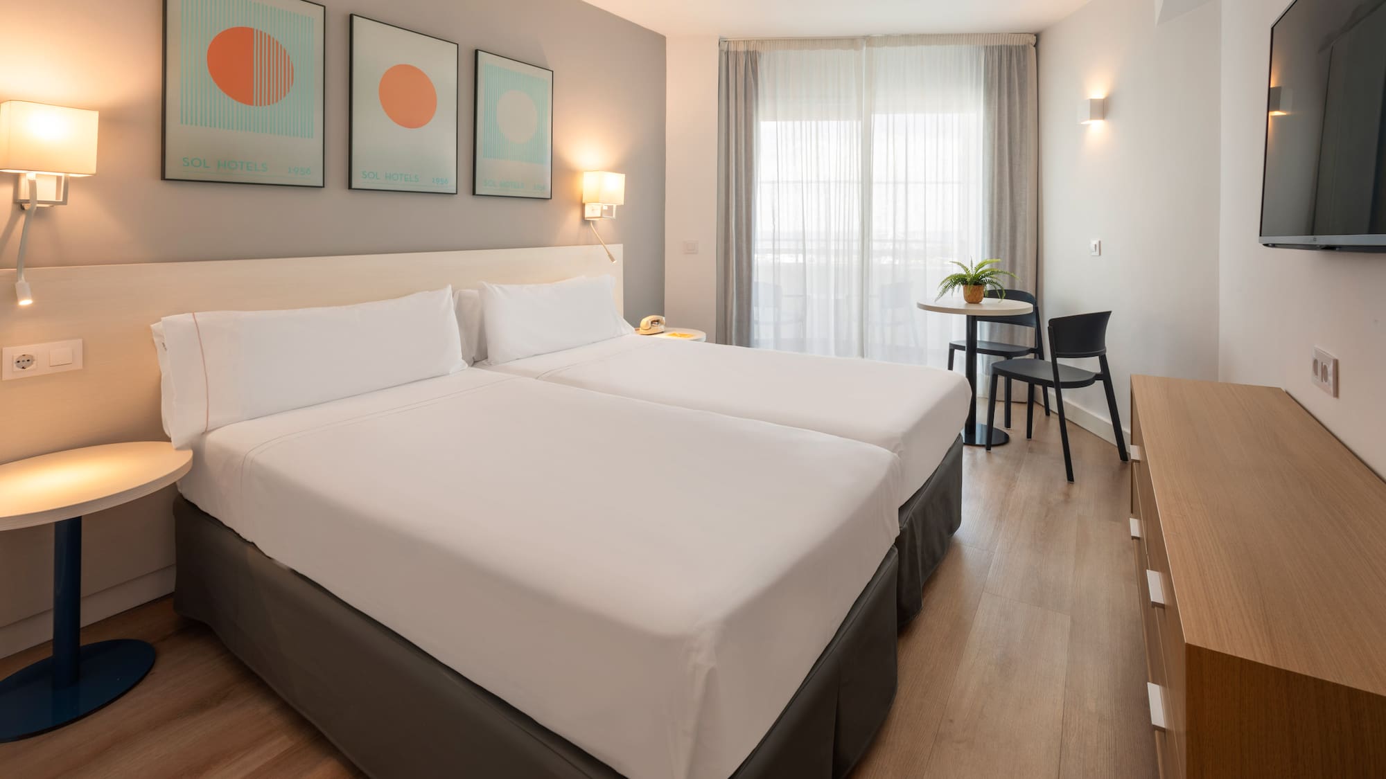 Habitación de hotel Sol con dos camas individuales, diseño moderno y ventanal.