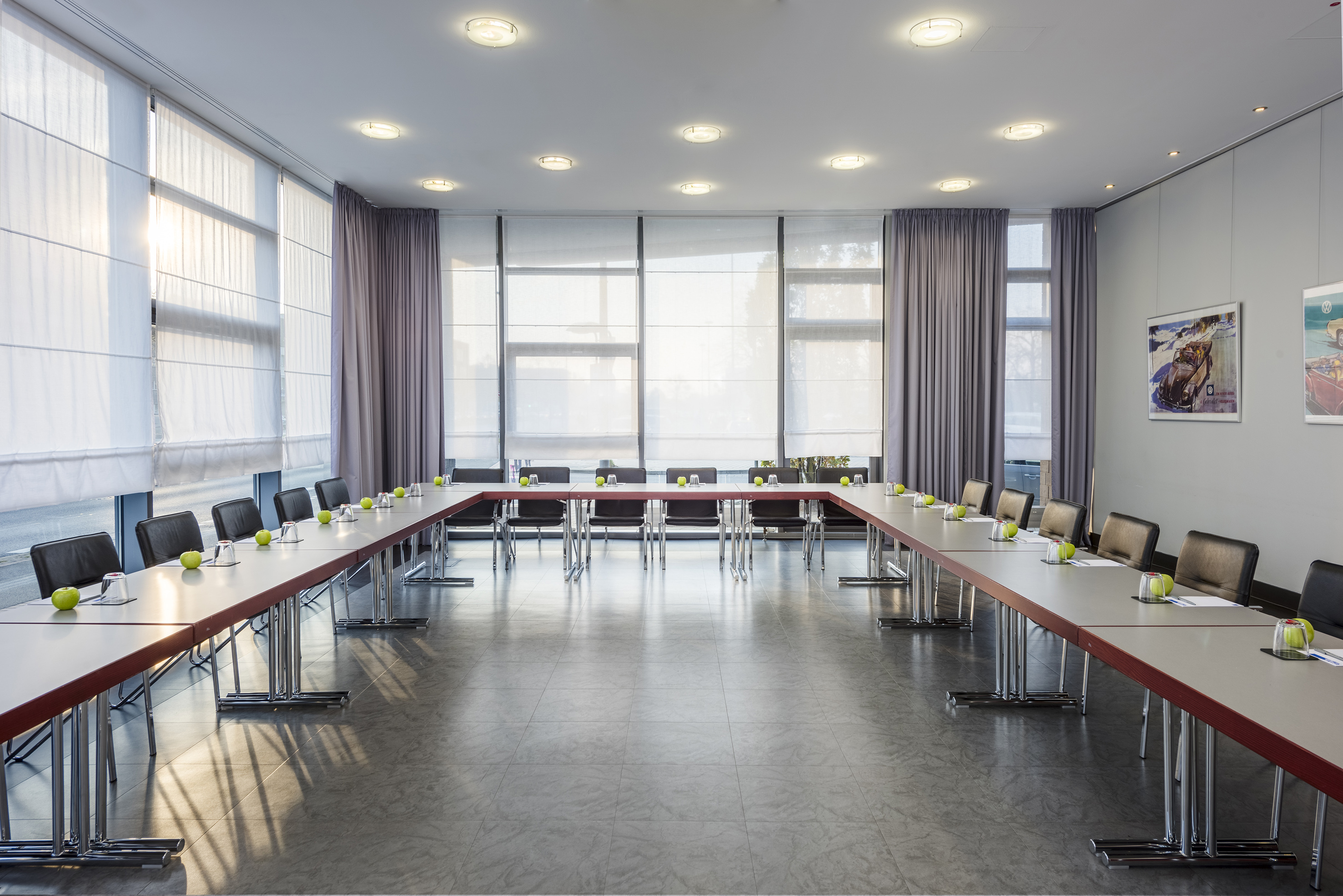 Modern U-shaped conference room with chairs, tables, and large windows.