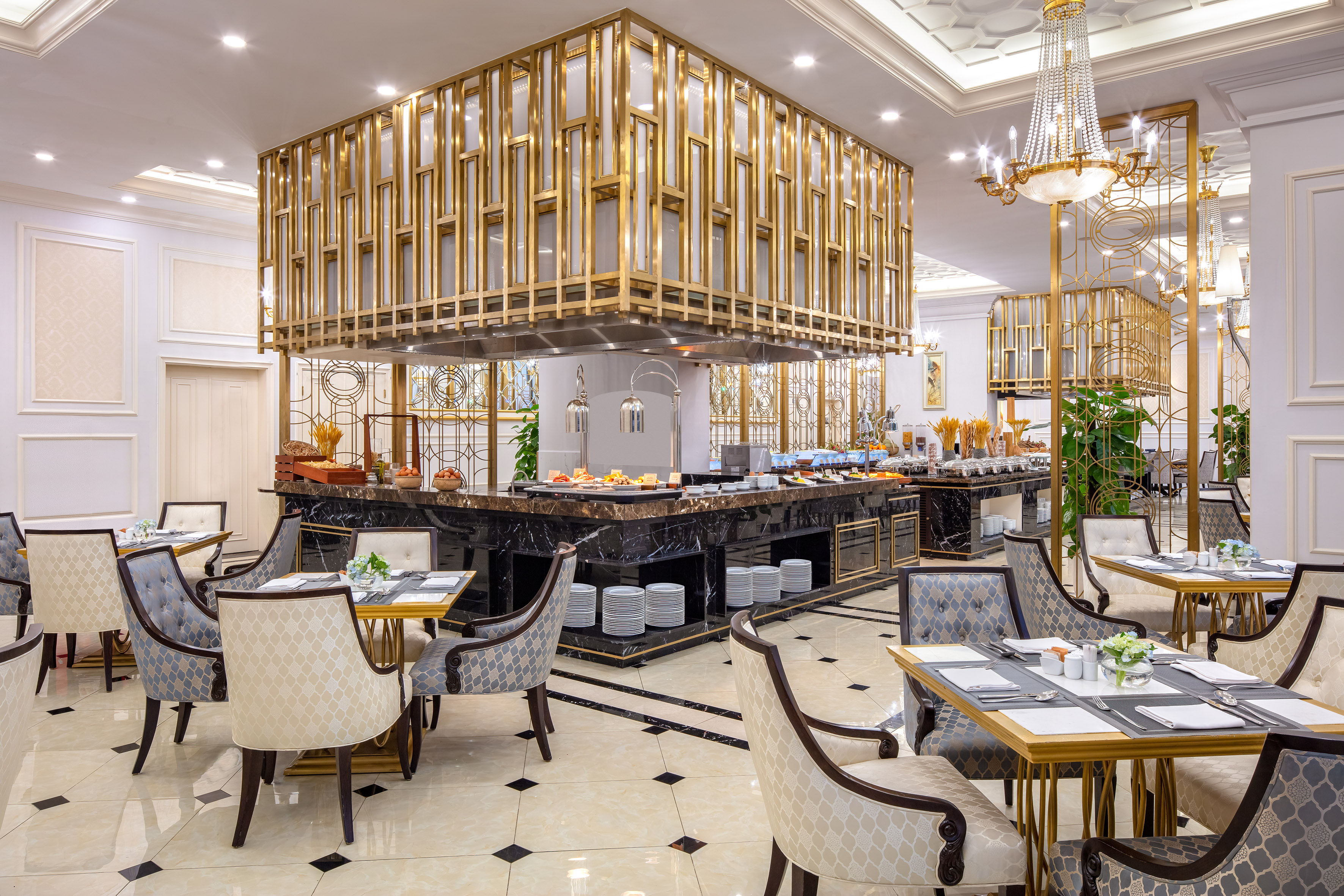 Luxury hotel buffet restaurant with gold decor and marble serving counters.