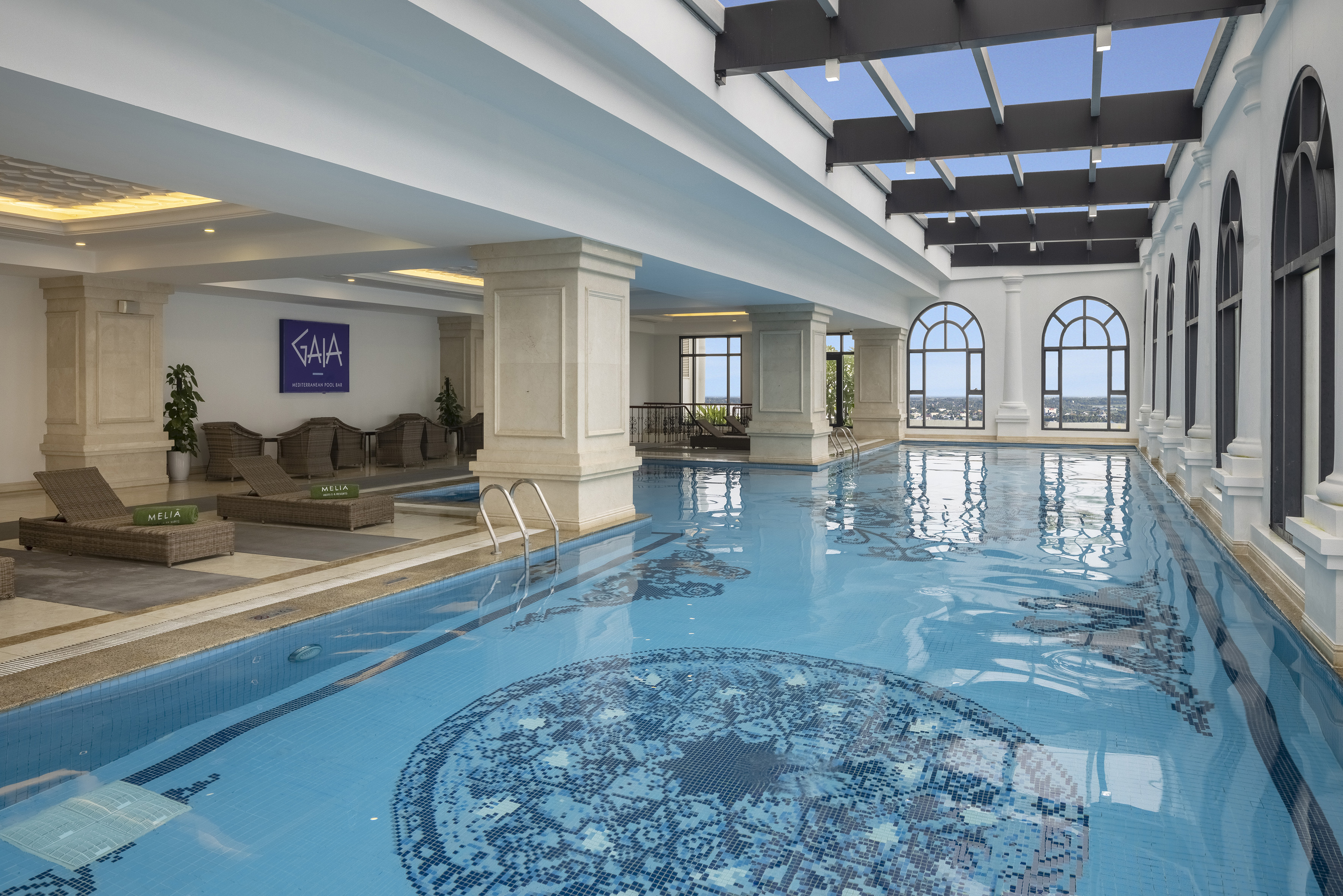 Luxury indoor GAIA Melia pool with mosaic, skylight, and city views.