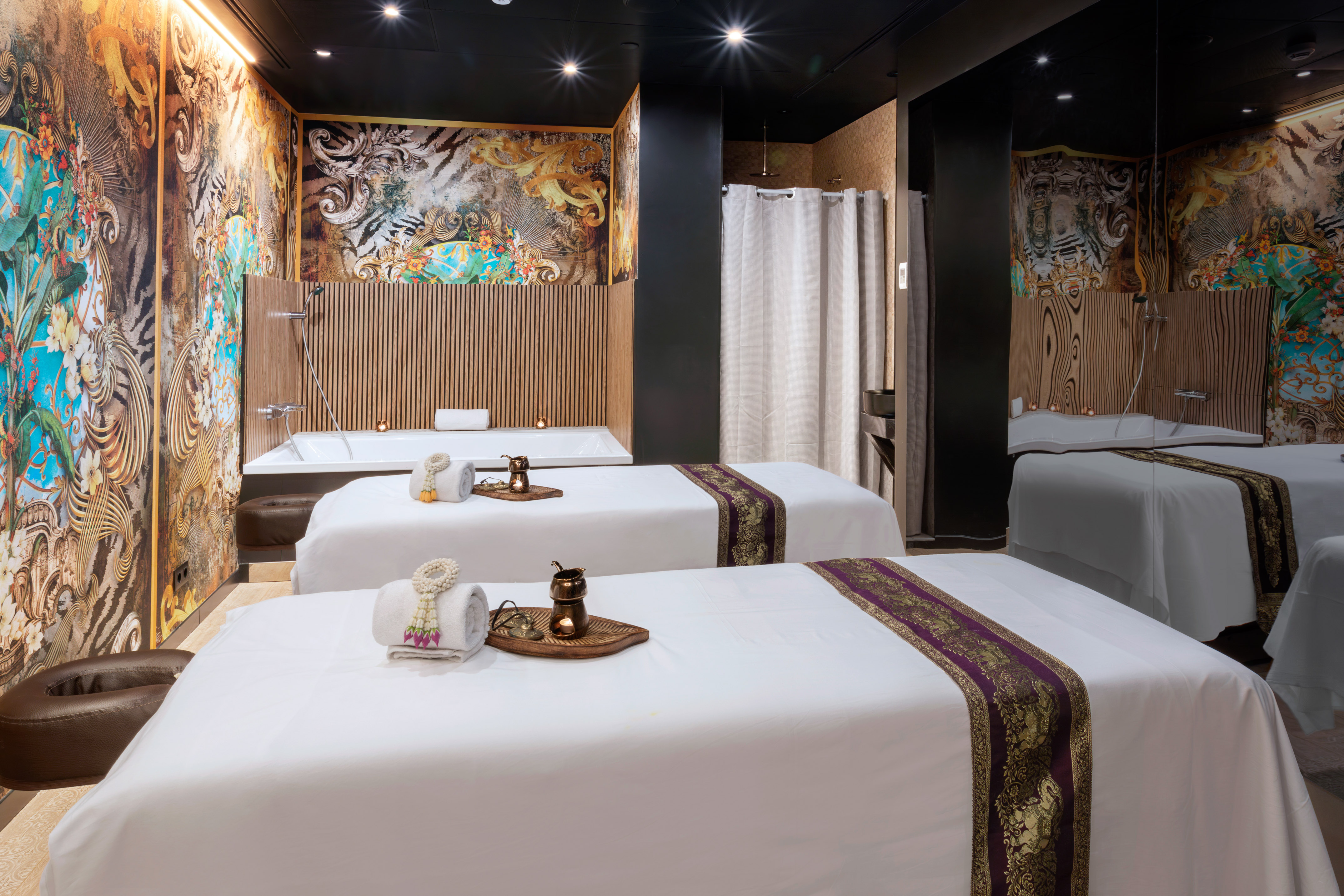 Luxury spa room, two massage tables, ornate wallpaper, bathtub, shower.
