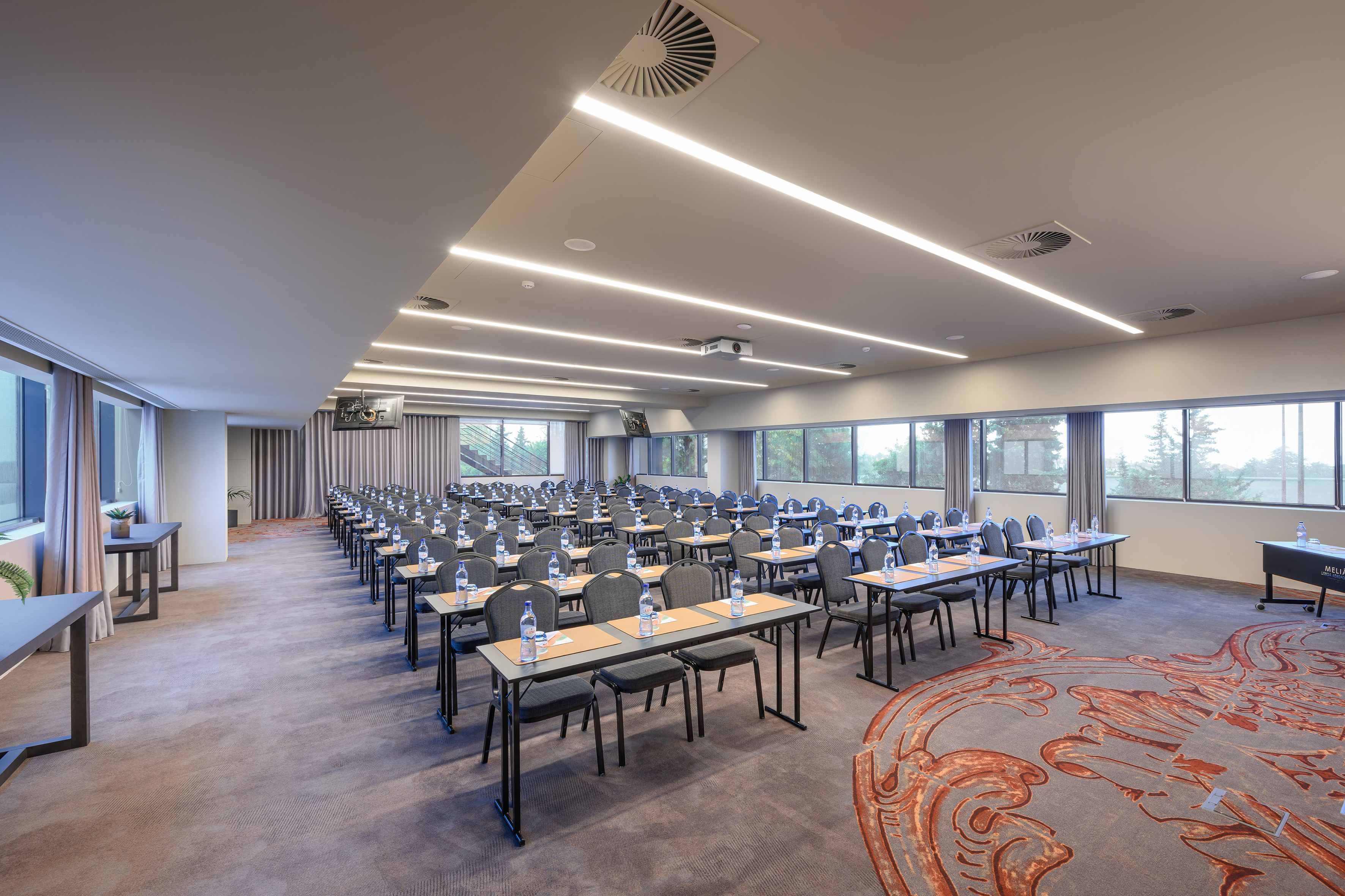 Spacious modern conference room with classroom setup, projector, and large windows.
