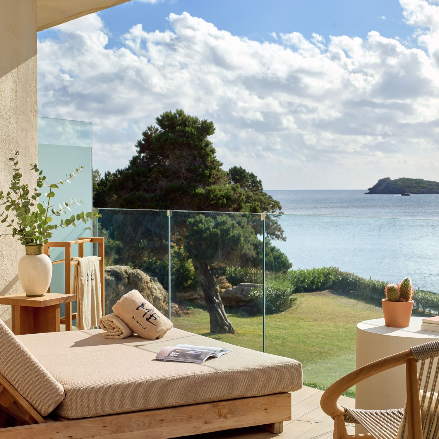 Luxurious balcony daybed with panoramic sea view, distant island, and blue sky.