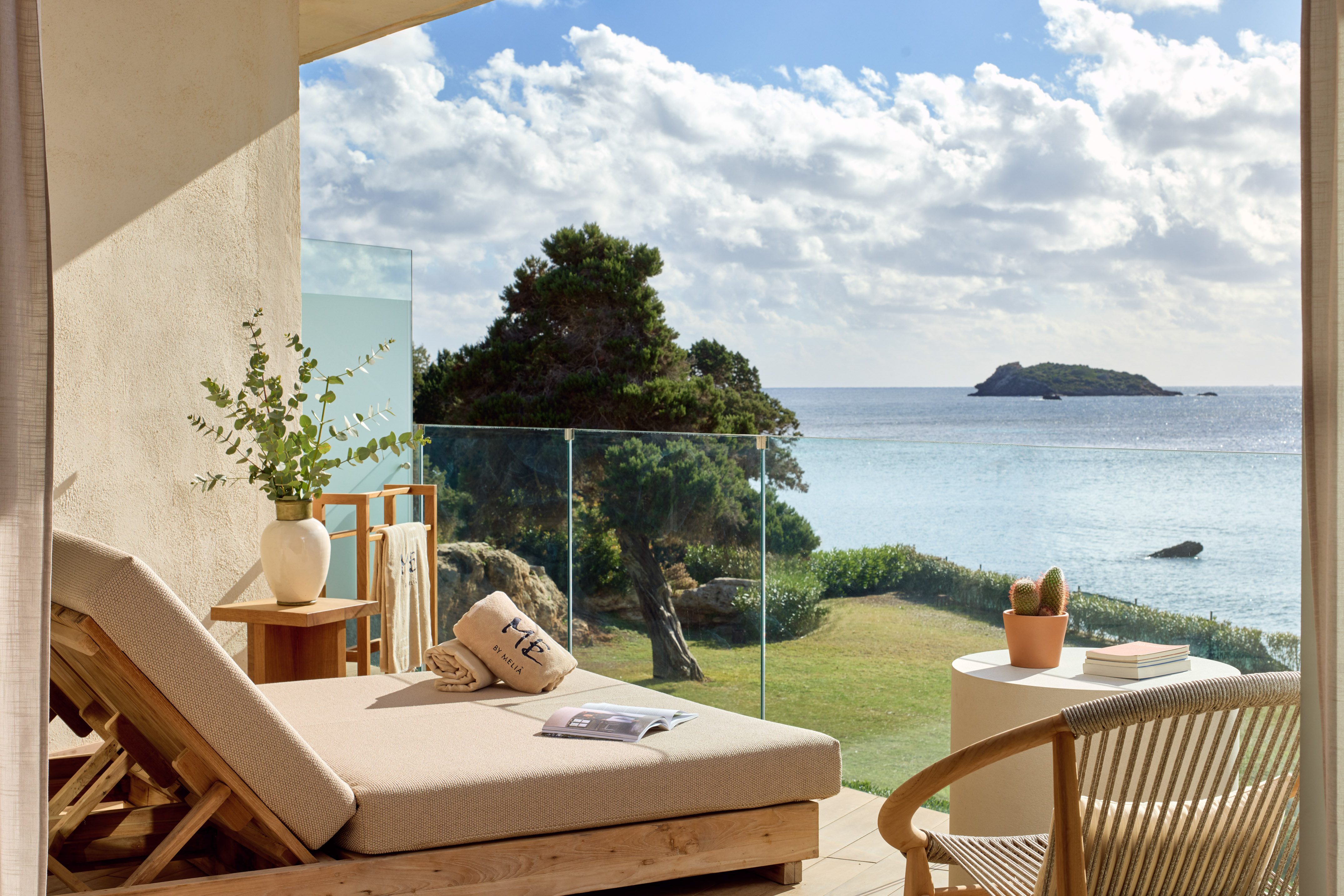 Luxurious balcony daybed with panoramic sea view, distant island, and blue sky.