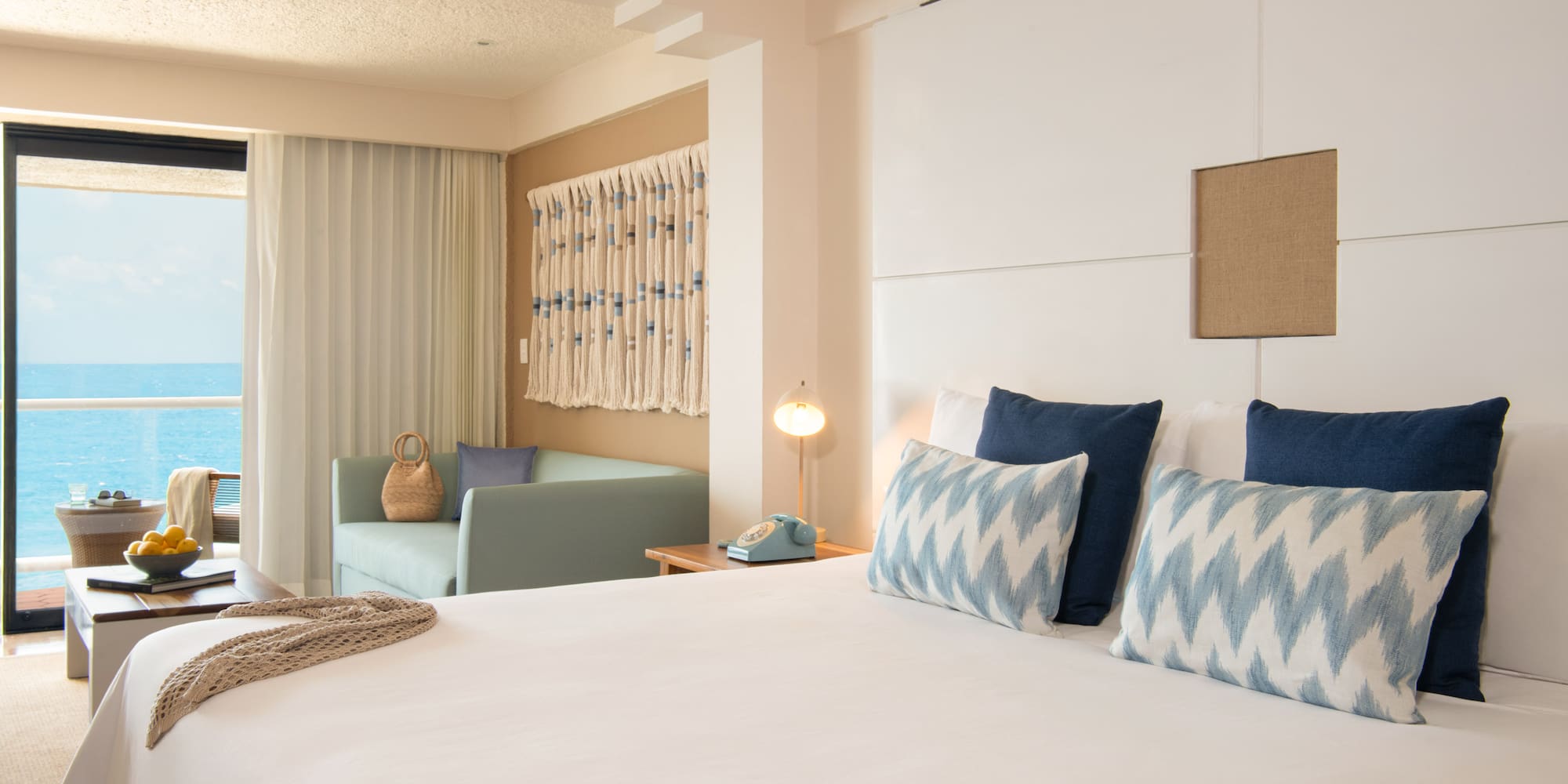 Resort room with ocean view, large bed, and coastal blue and white decor.