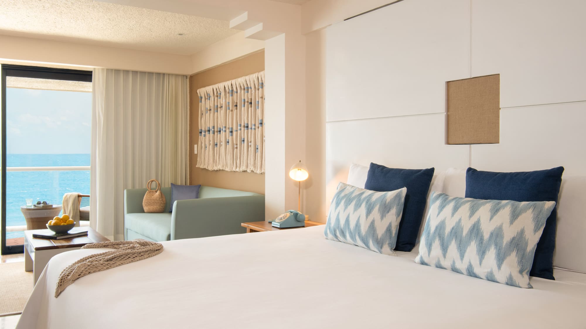 Resort room with ocean view, large bed, and coastal blue and white decor.