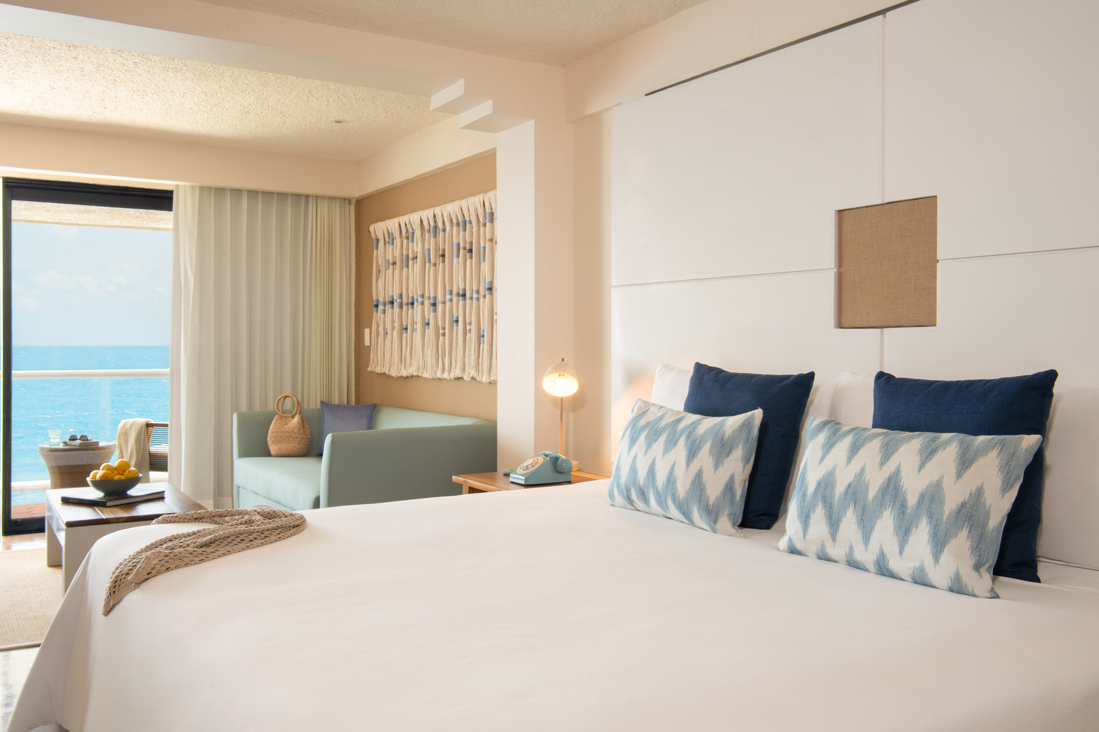 Resort room with ocean view, large bed, and coastal blue and white decor.