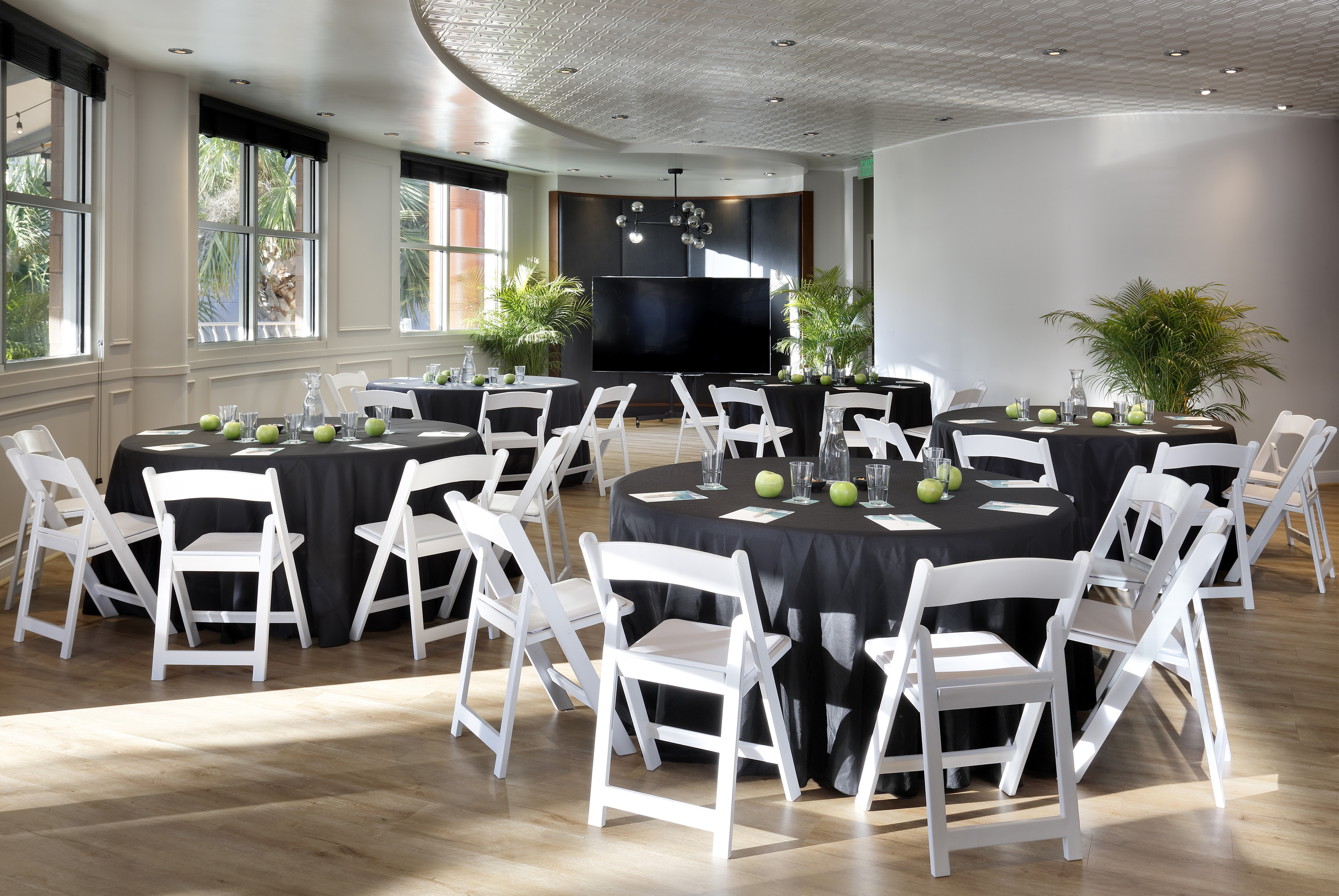Modern meeting room with black tables, white chairs, screen, and natural light. - The Pearl (circular floor plan) - Meliá Orlando Celebration, Orlando
