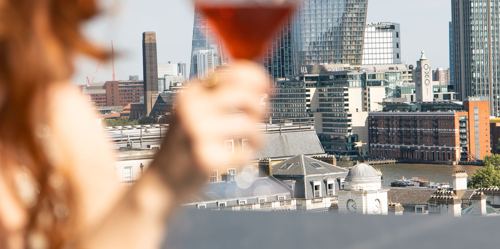 a woman holding a glass with a city in the background