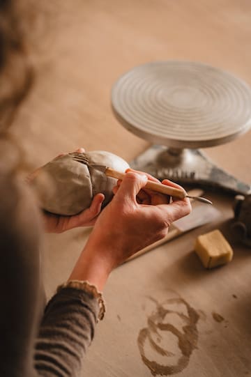 a person using a tool to sculpt a clay object