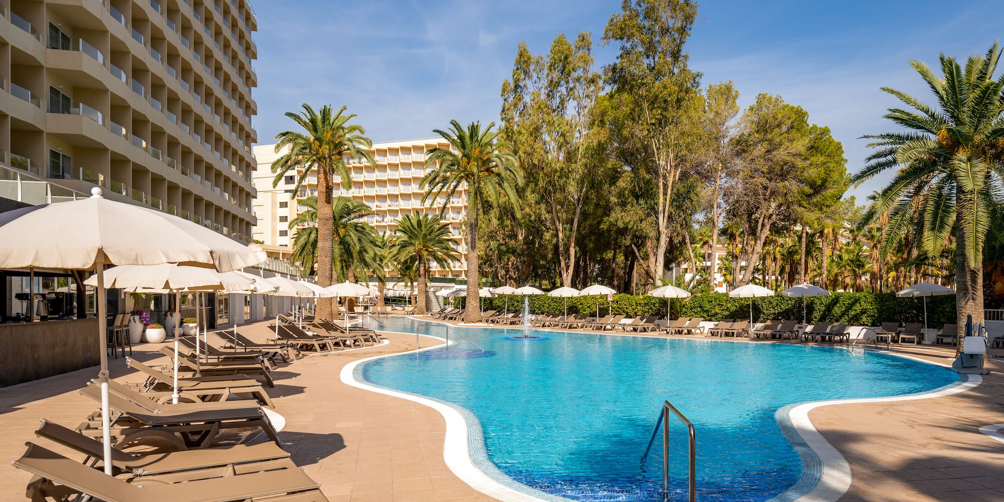 a pool with lounge chairs and umbrellas in front of a building