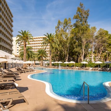 a pool with lounge chairs and umbrellas in front of a building
