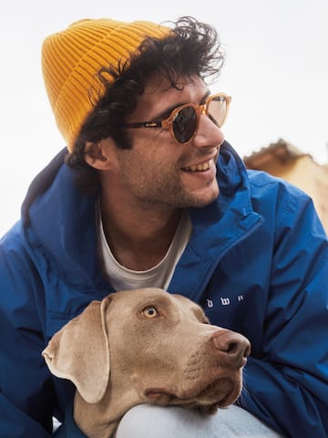 a man wearing a hat and sunglasses with a dog