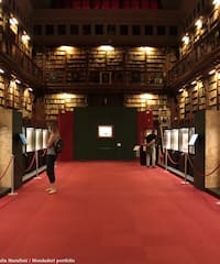 people in a library with red carpet and red rope barriers