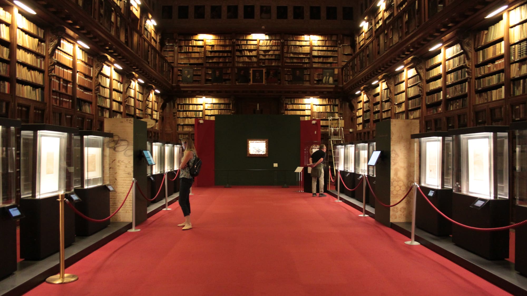 people in a library with red carpet and red rope barriers