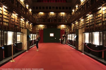 people in a library with red carpet and red rope barriers