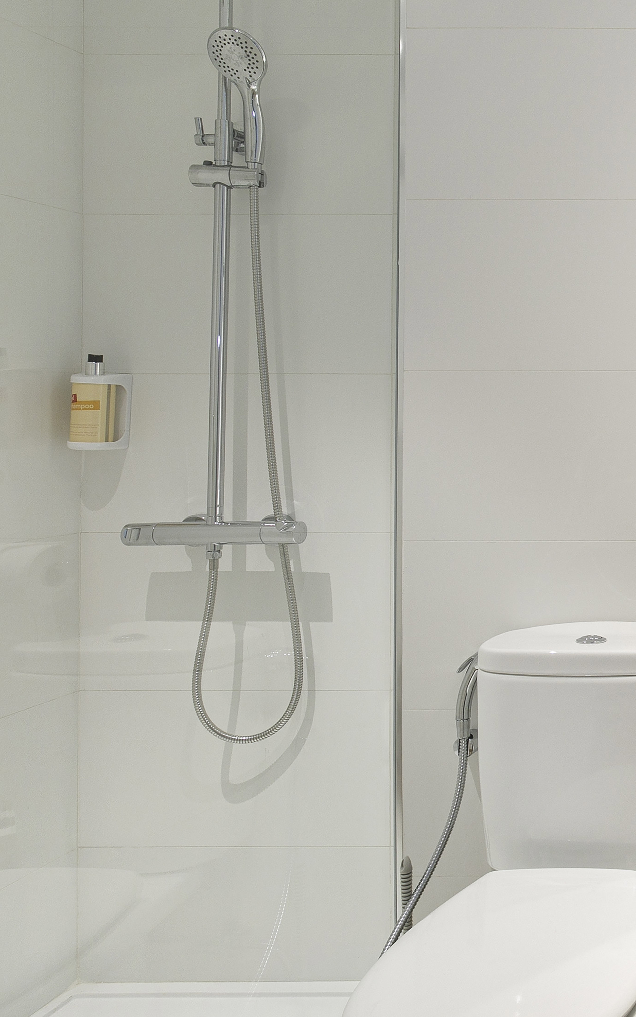 Modern bathroom with white shower, chrome fixtures, and toilet with bidet.