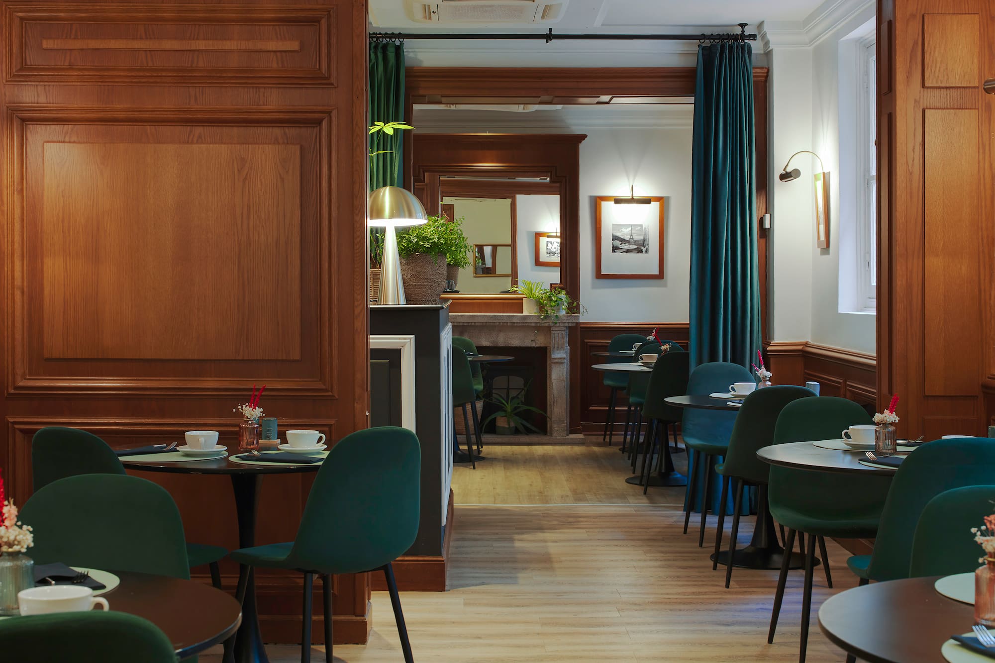 Elegant hotel dining room with green chairs, wooden walls, and set tables.