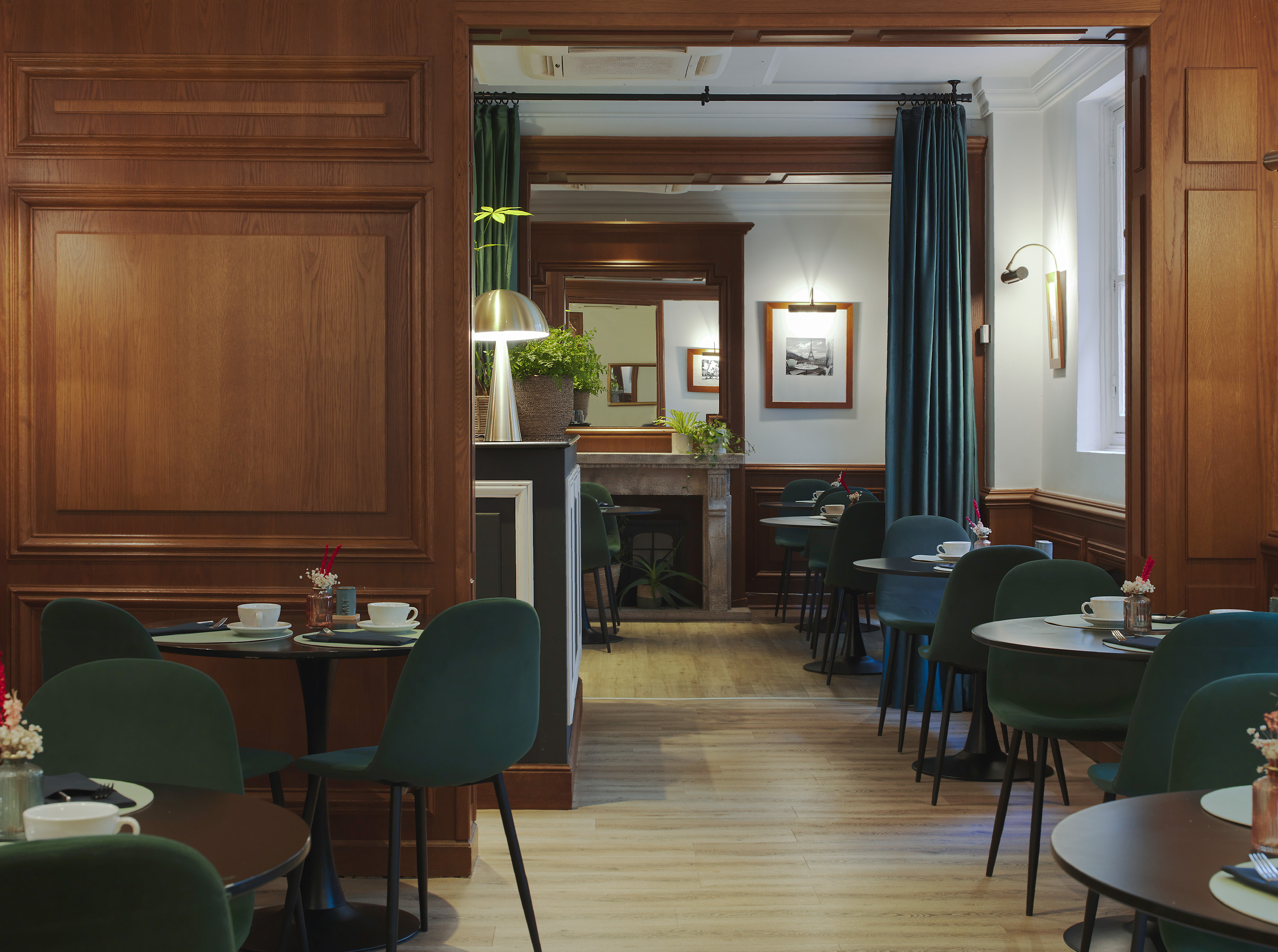 Elegant hotel dining room with green chairs, wooden walls, and set tables.