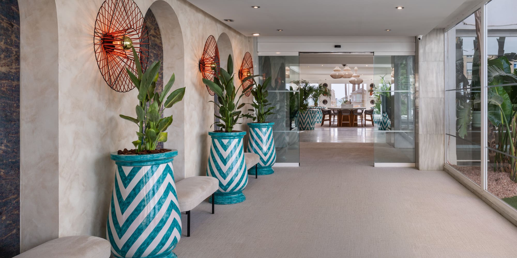 Stylish hotel lobby with arched walls, chevron planters, and modern lights.