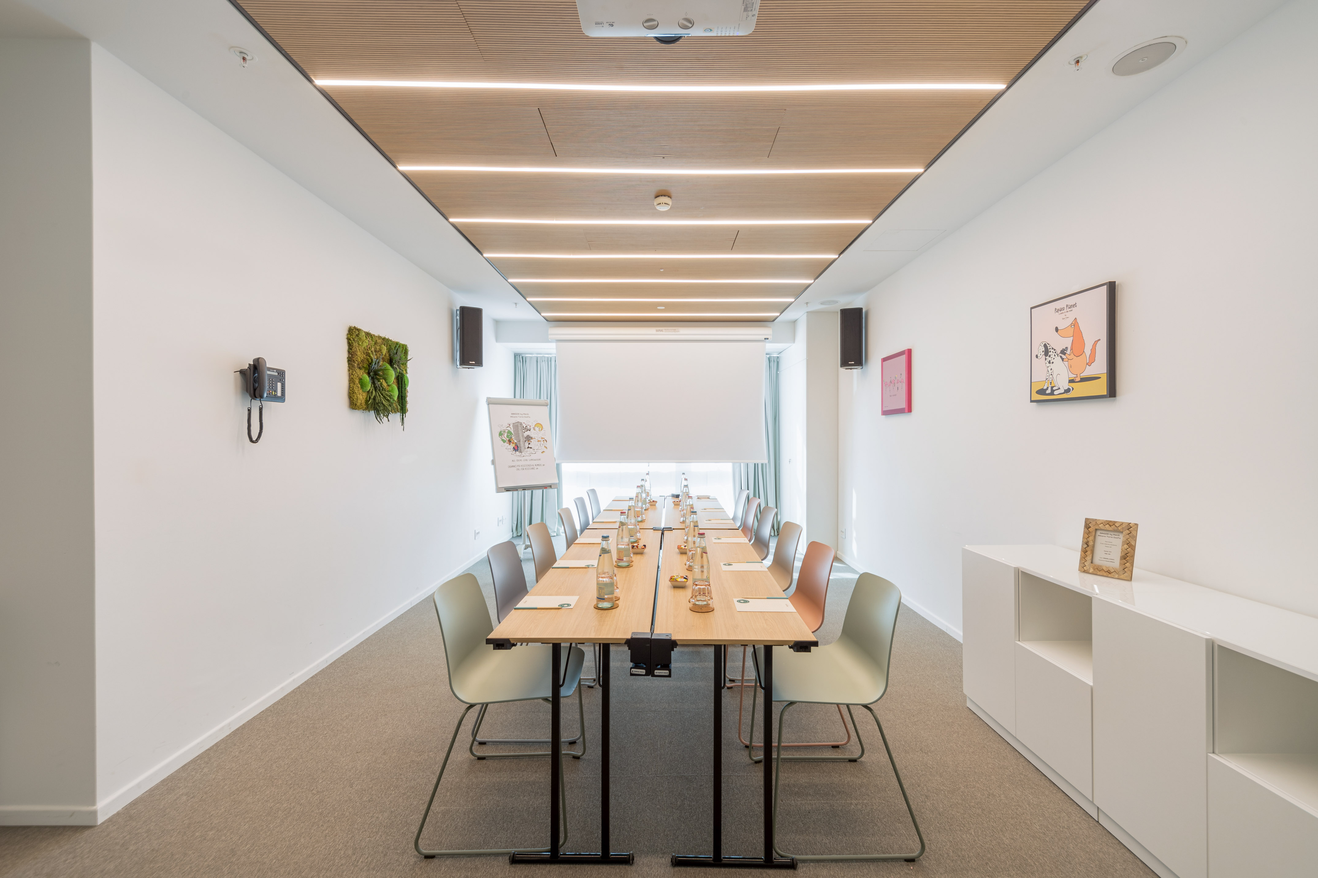 Modern conference room with long table, chairs, projector, and wooden slatted ceiling.