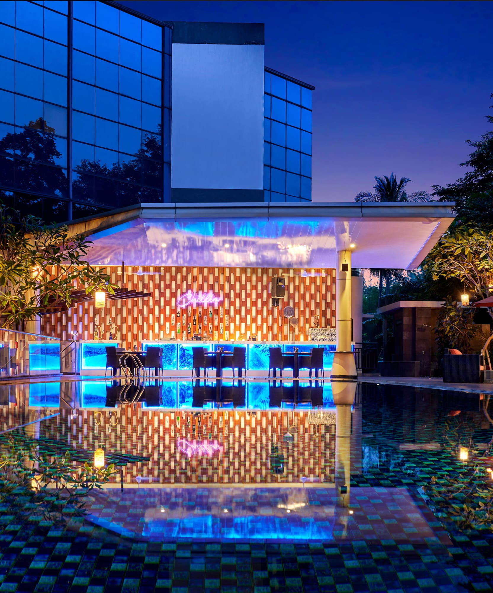 a pool with tables and chairs in front of a building
