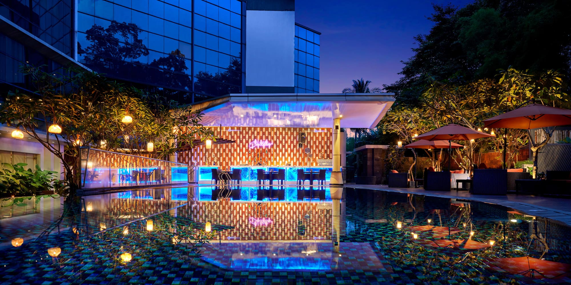 a pool with tables and chairs in front of a building