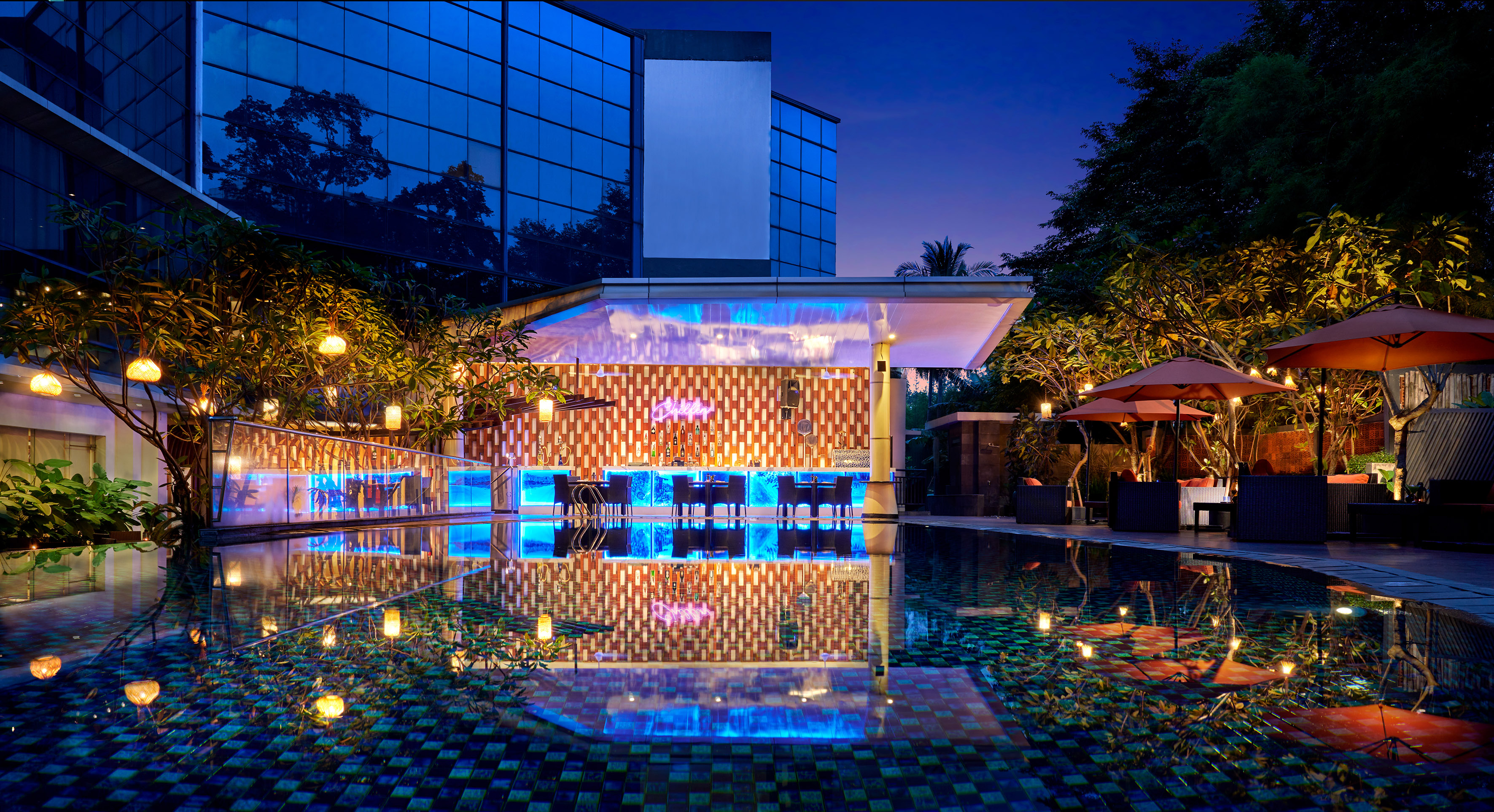 a pool with tables and chairs in front of a building