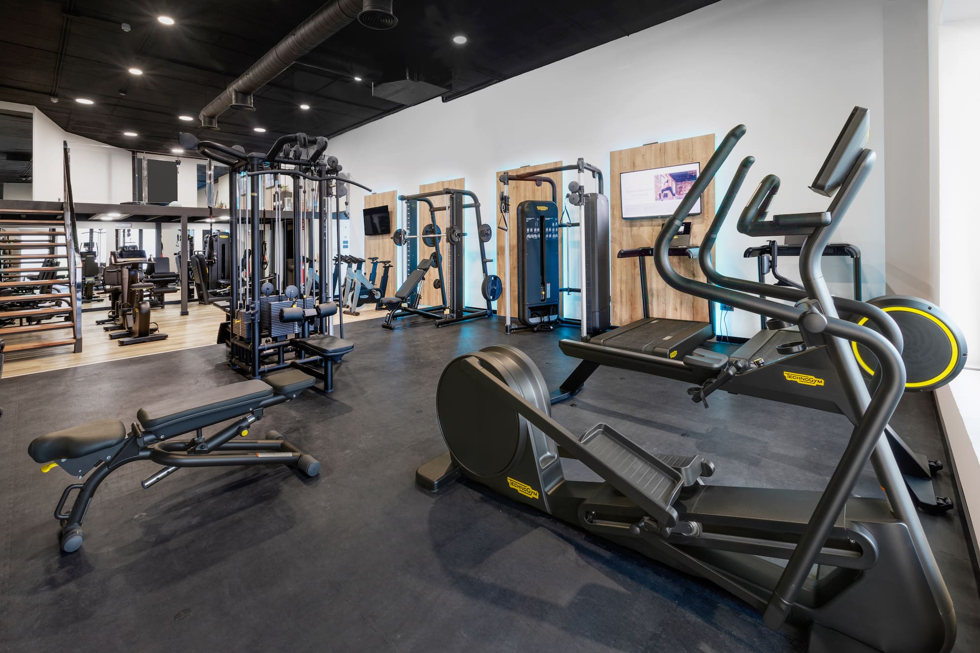 Spacious modern gym with cardio and strength training exercise equipment.