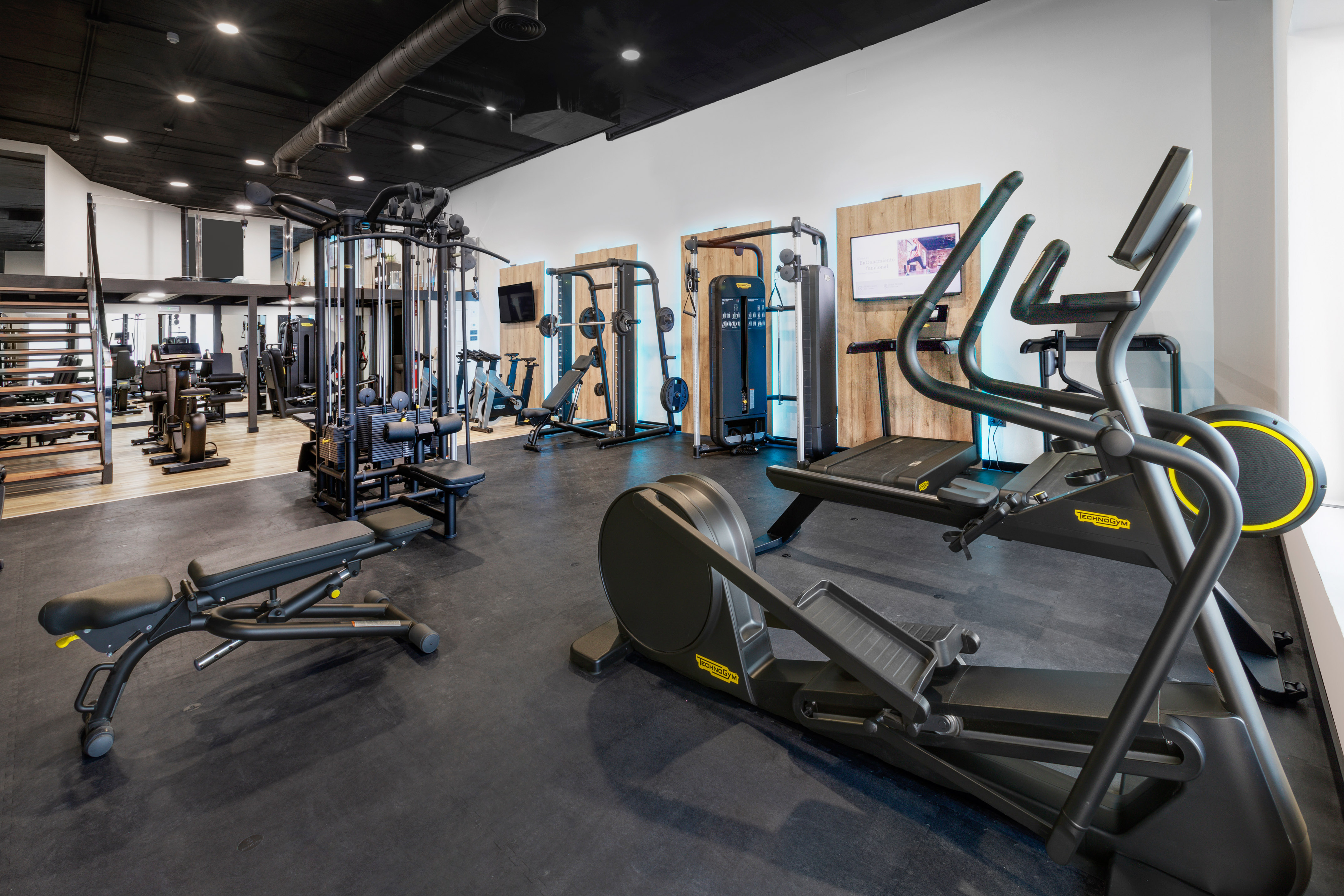 Spacious modern gym with cardio and strength training exercise equipment.