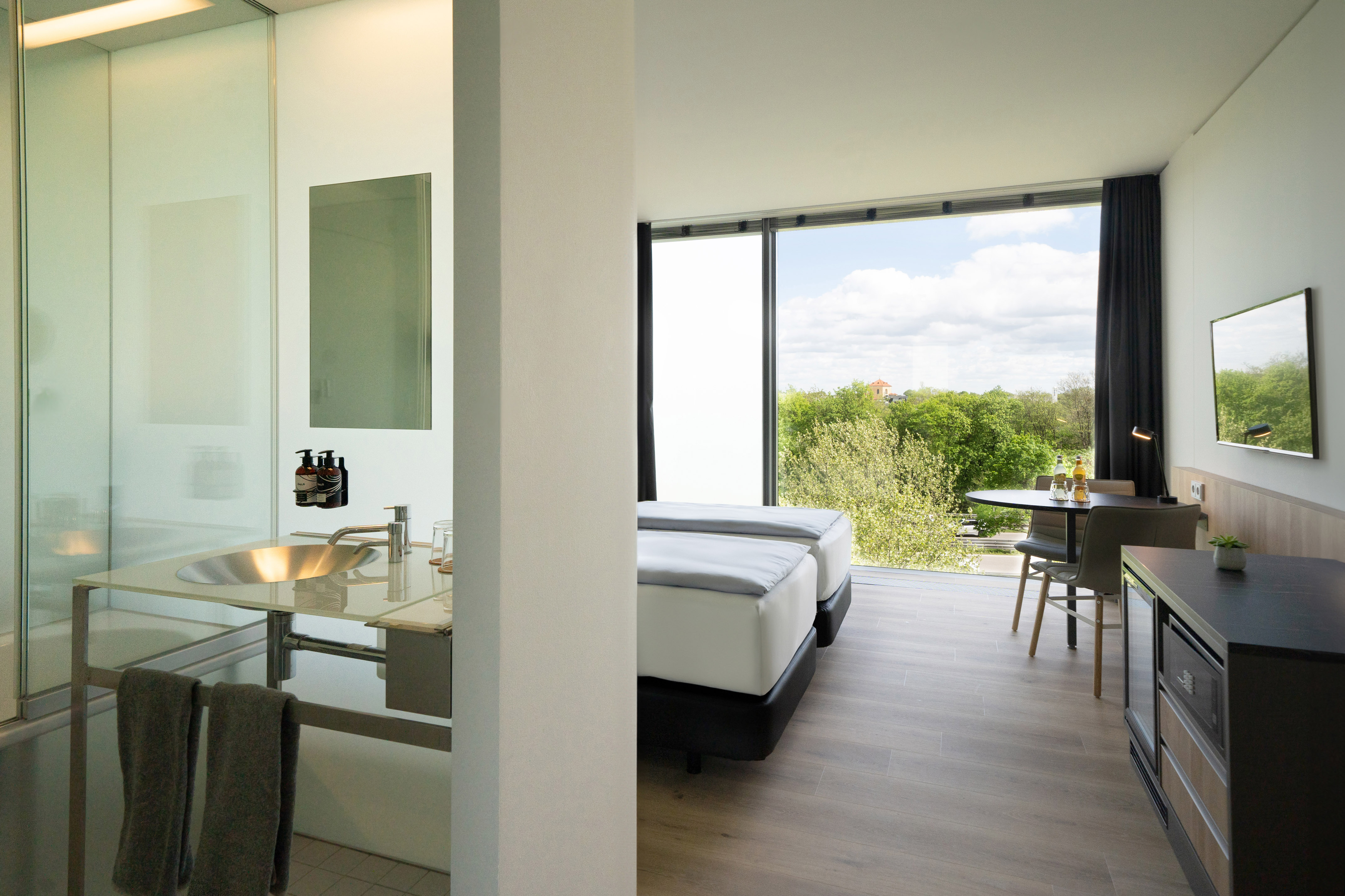 Hotel room with twin beds, modern bathroom, and scenic window view.