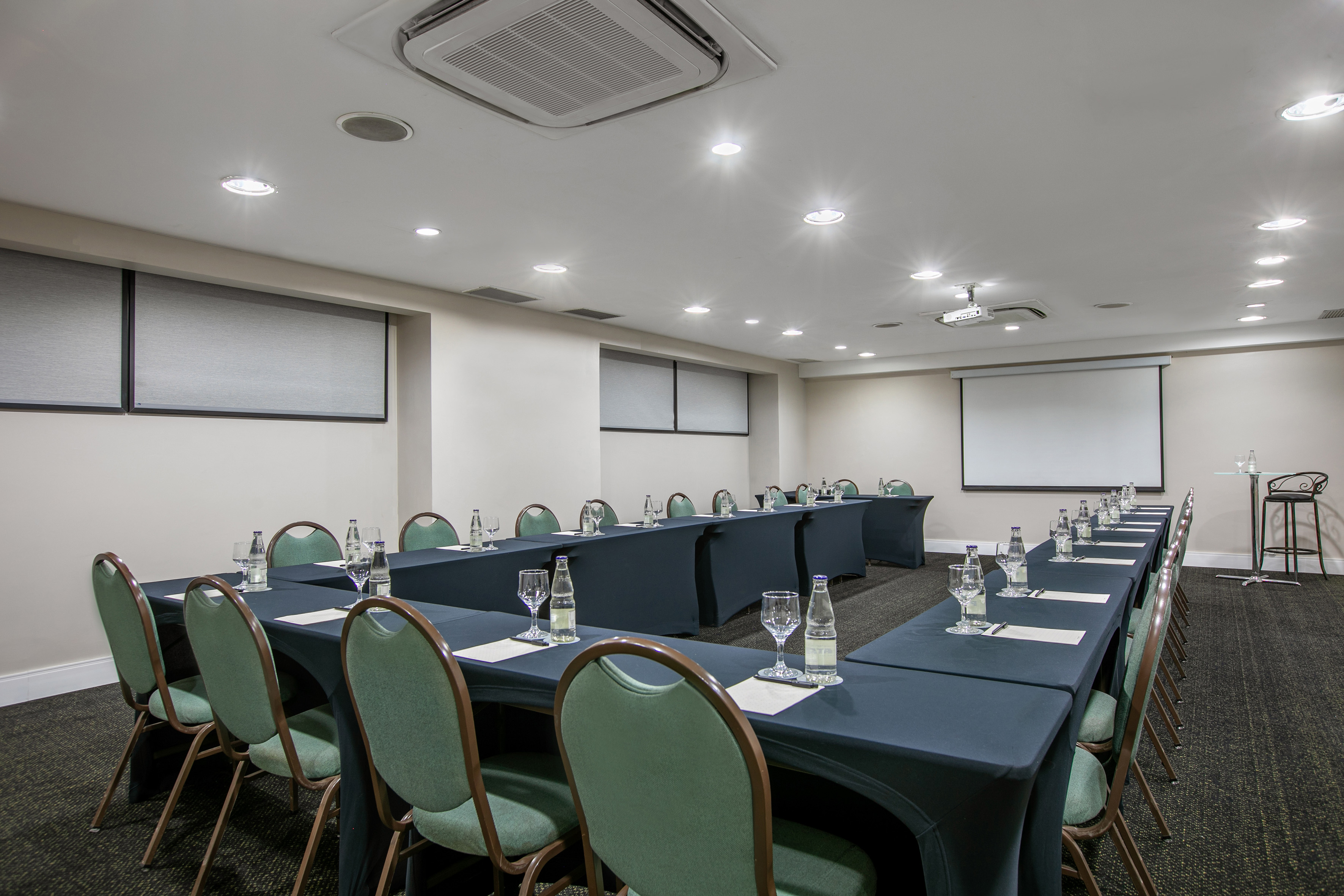 U-shape meeting room setup with projector screen and individual place settings.