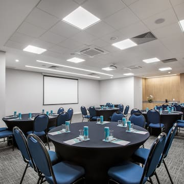 a room with round tables and blue chairs