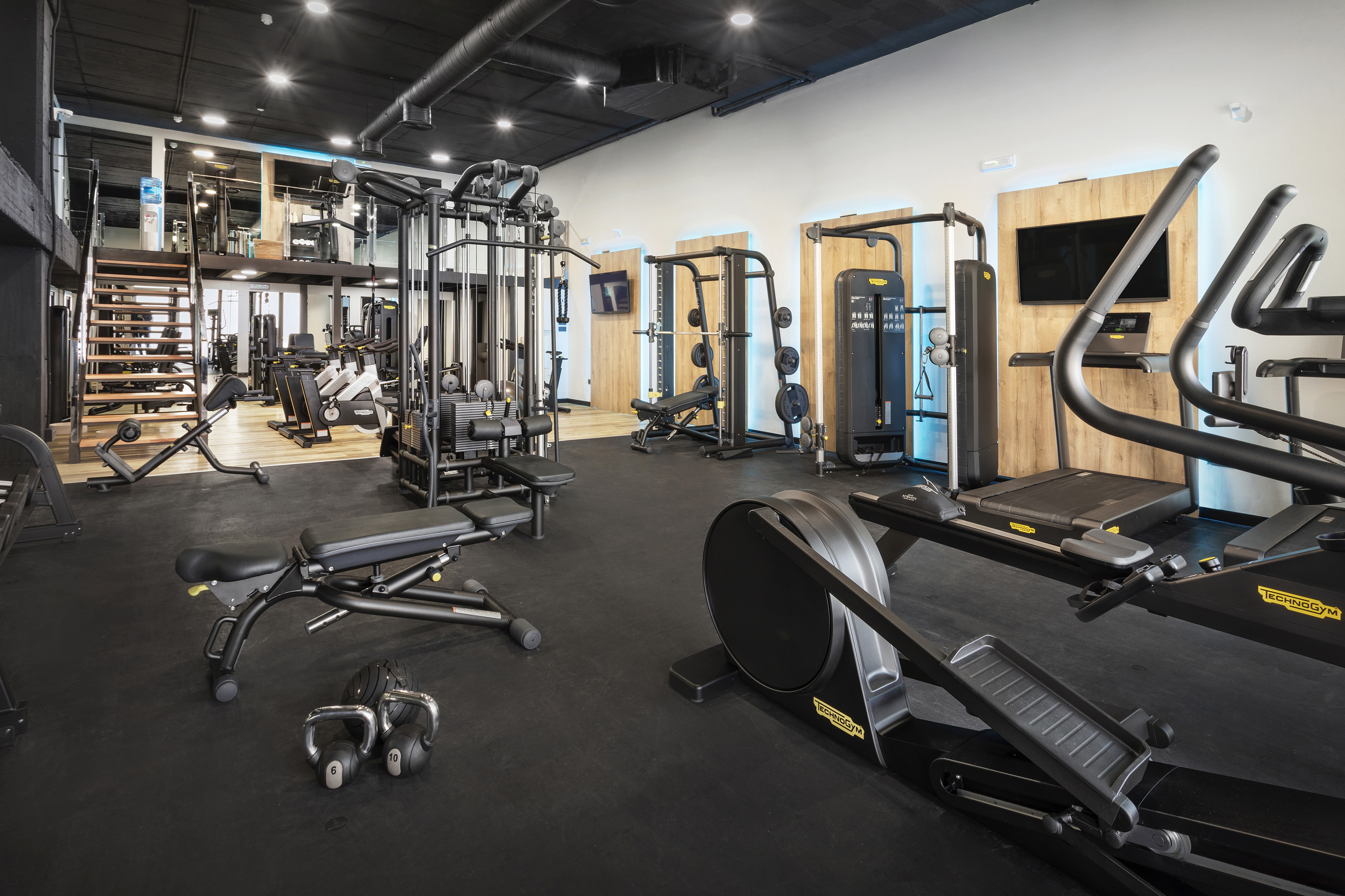 Well-equipped modern gym interior with cardio and strength machines, black floor.