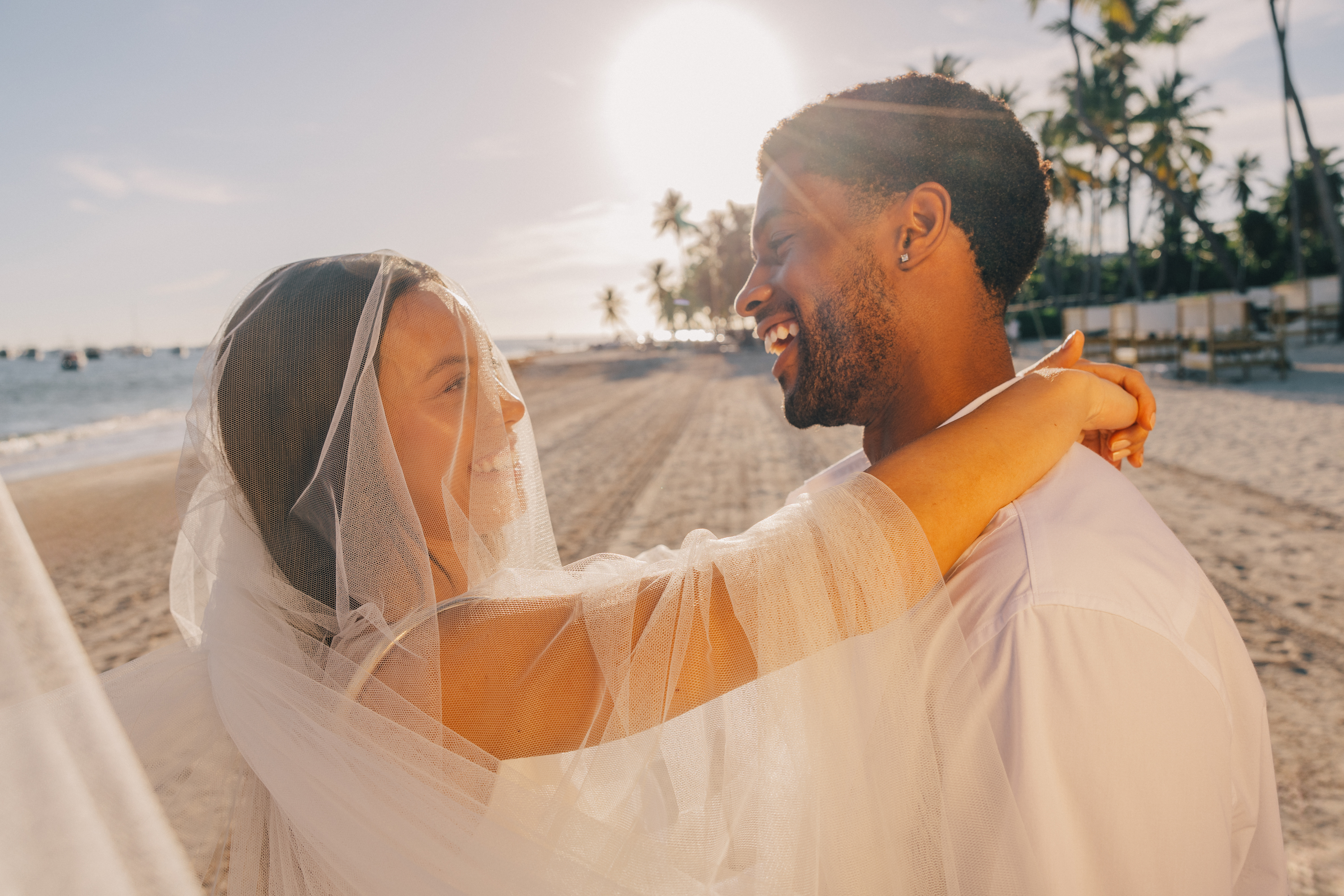 a man and woman in white dress dancing on a beach