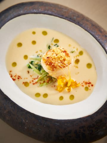 a bowl of soup with a scallop on top