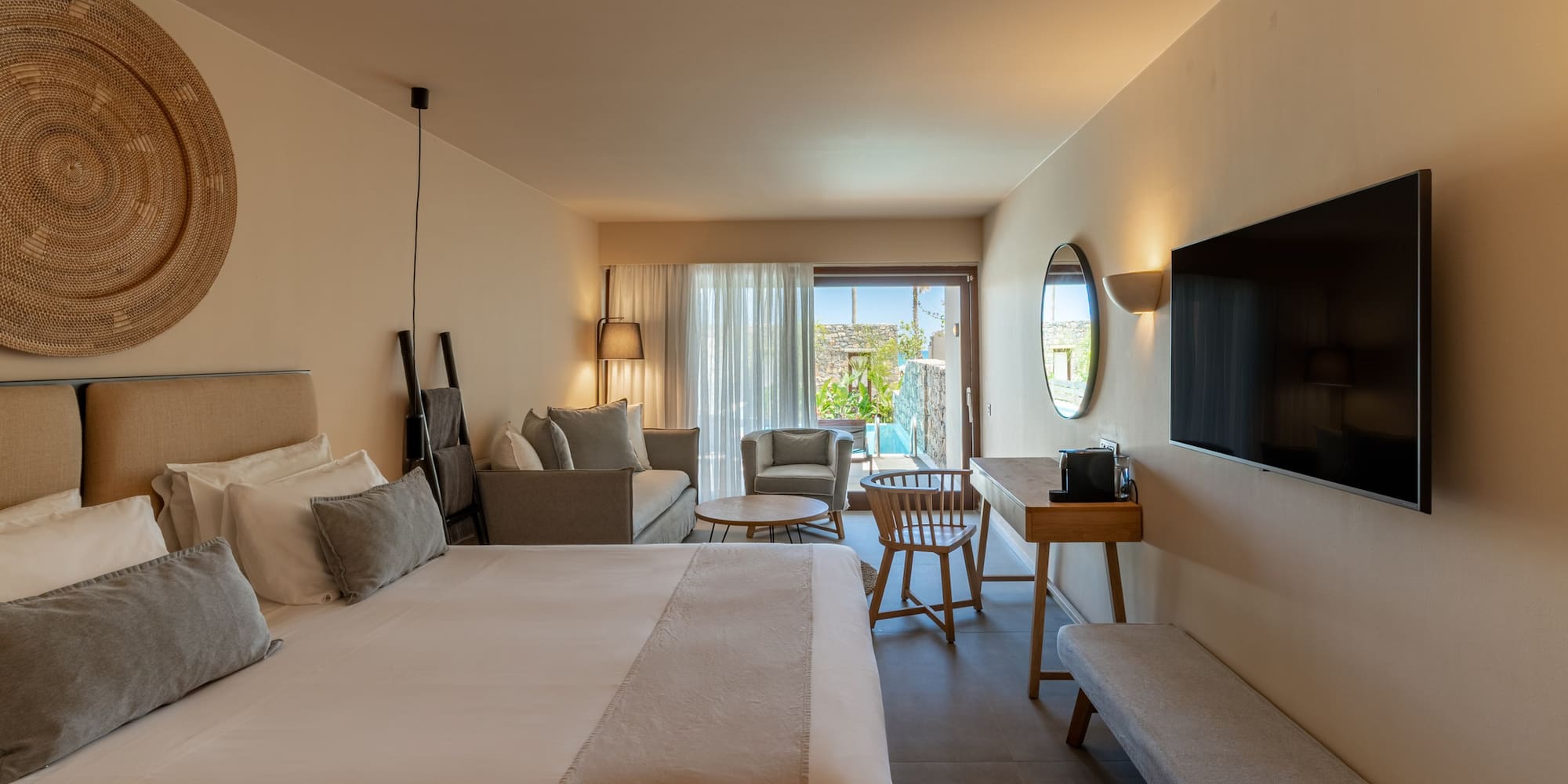 Contemporary hotel suite with bed, sitting area, TV, and private outdoor pool.