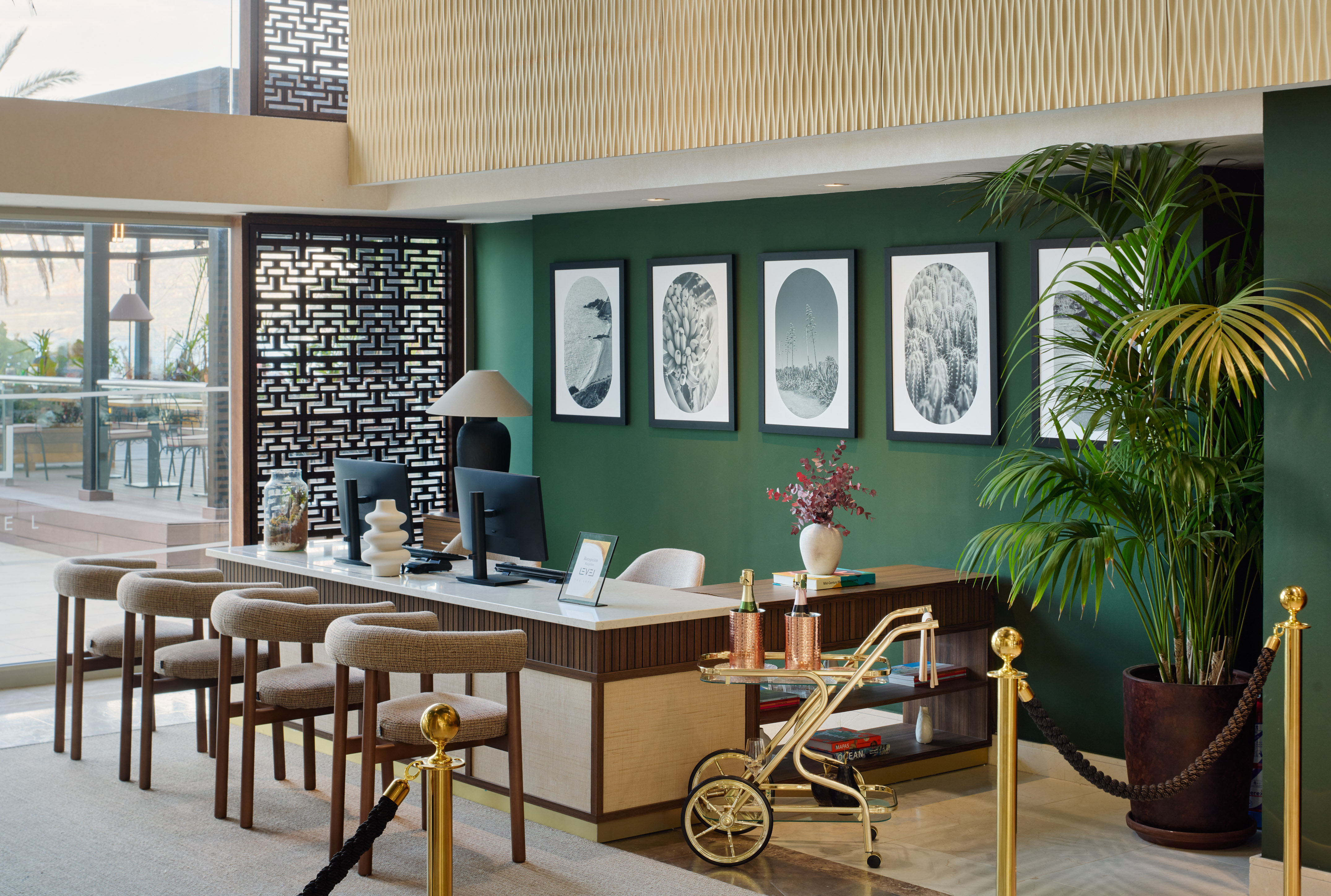 Hotel reception lobby with elegant desk, green wall art, and modern decor.