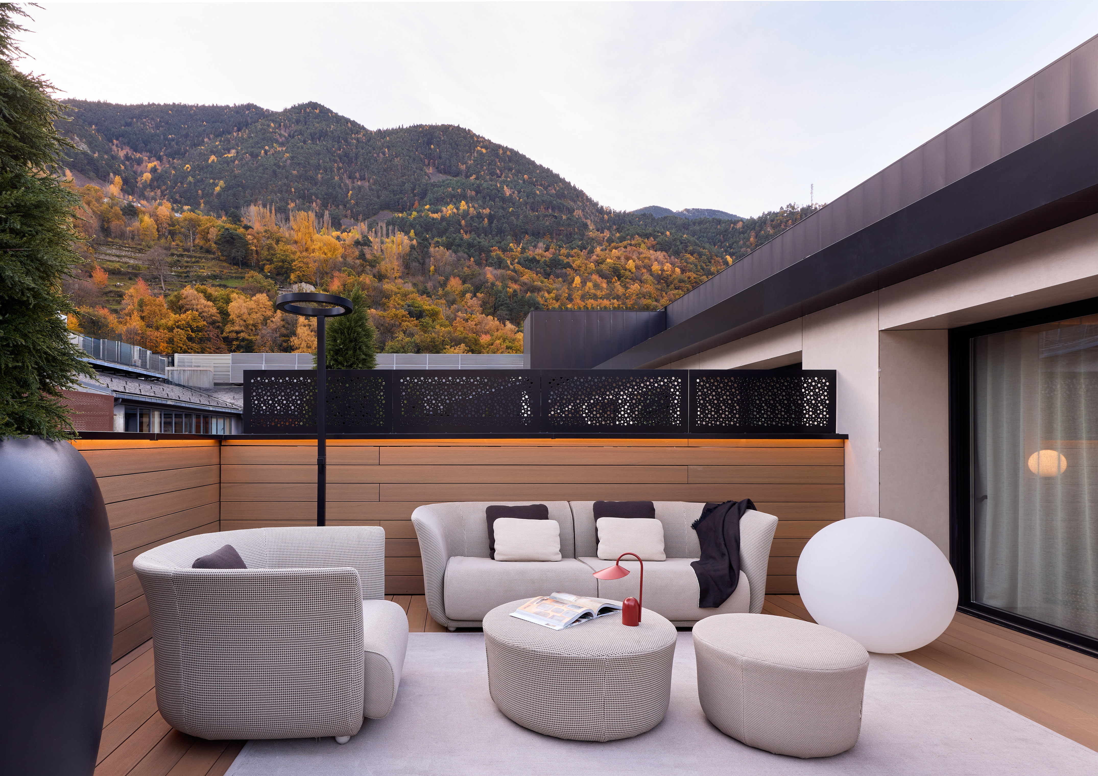 Rooftop terrace with modern gray furniture and a backdrop of autumn mountains.