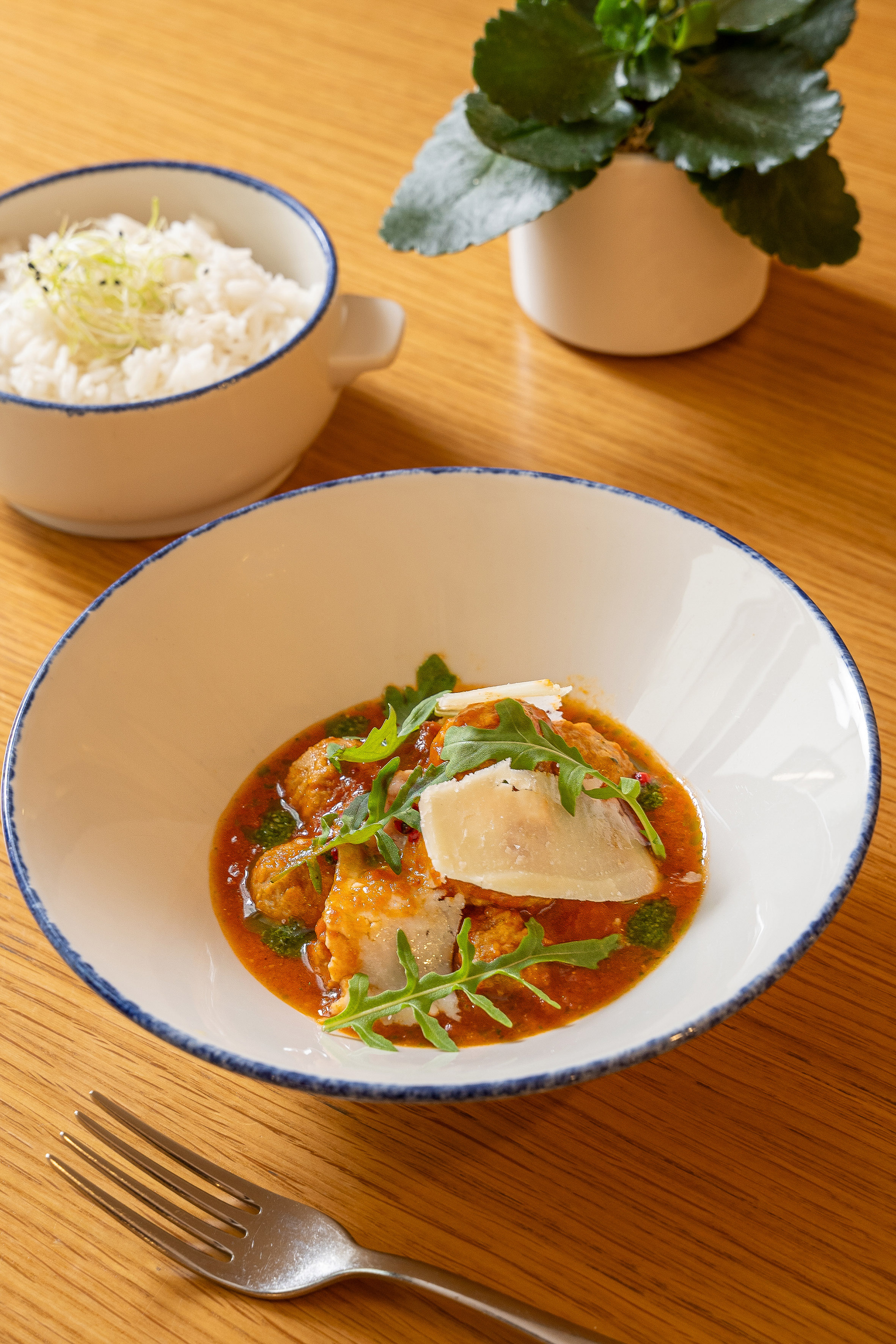 Meatballs in tomato sauce with parmesan and arugula, served with white rice.