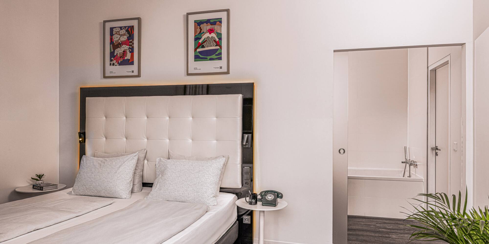 Contemporary hotel room with twin beds, framed art, and an ensuite bathroom.