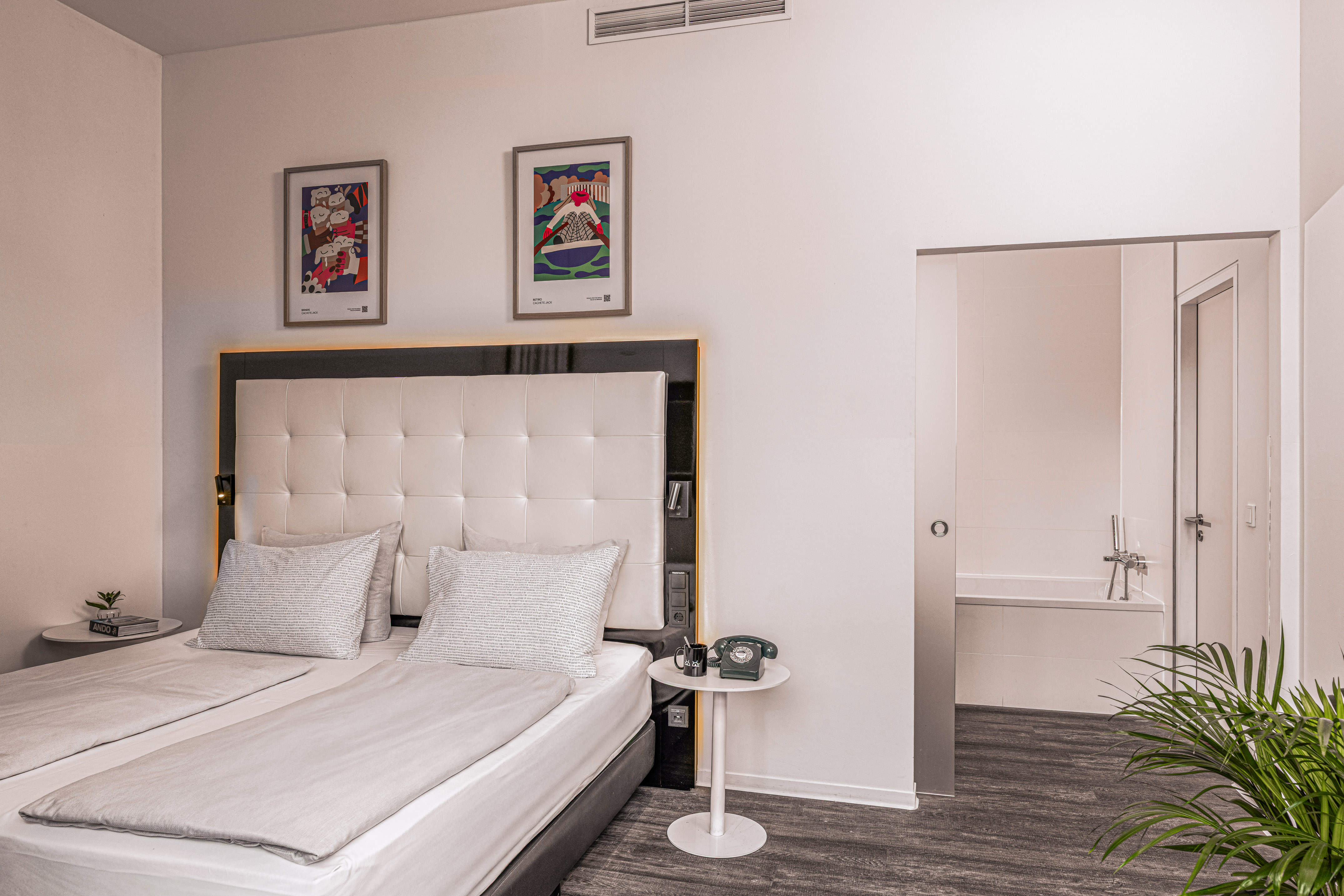 Contemporary hotel room with twin beds, framed art, and an ensuite bathroom.