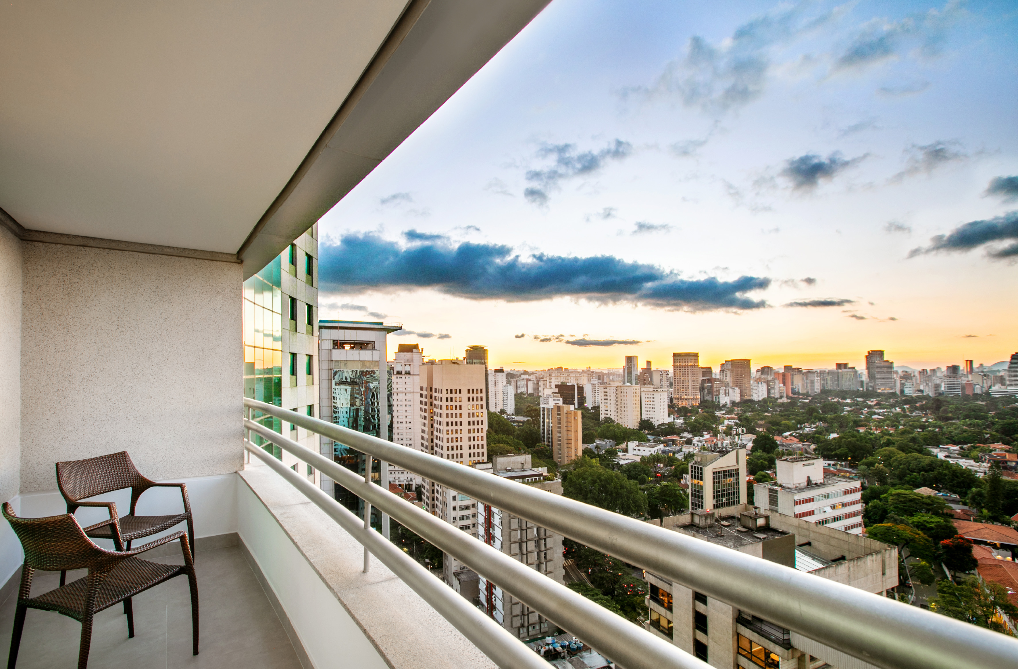 Modern balcony offering expansive city skyline view during sunset.