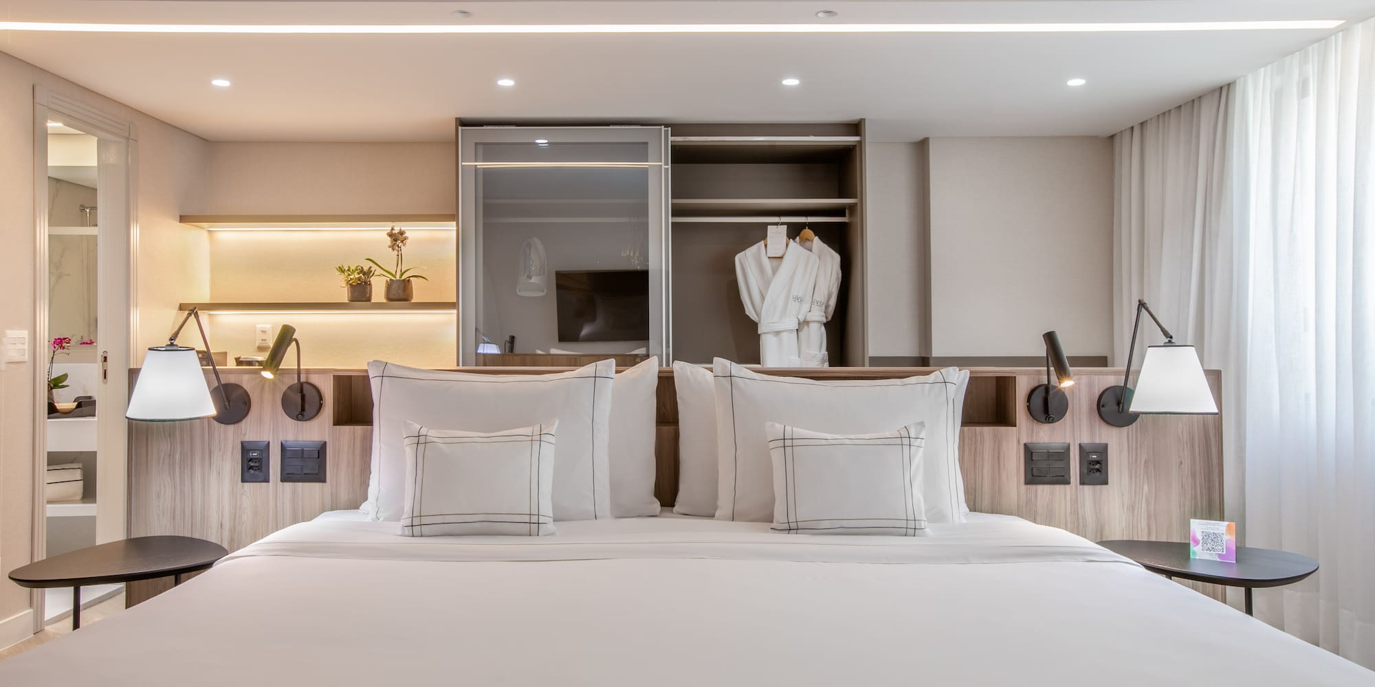 a bed with white pillows and a white robe on the wall