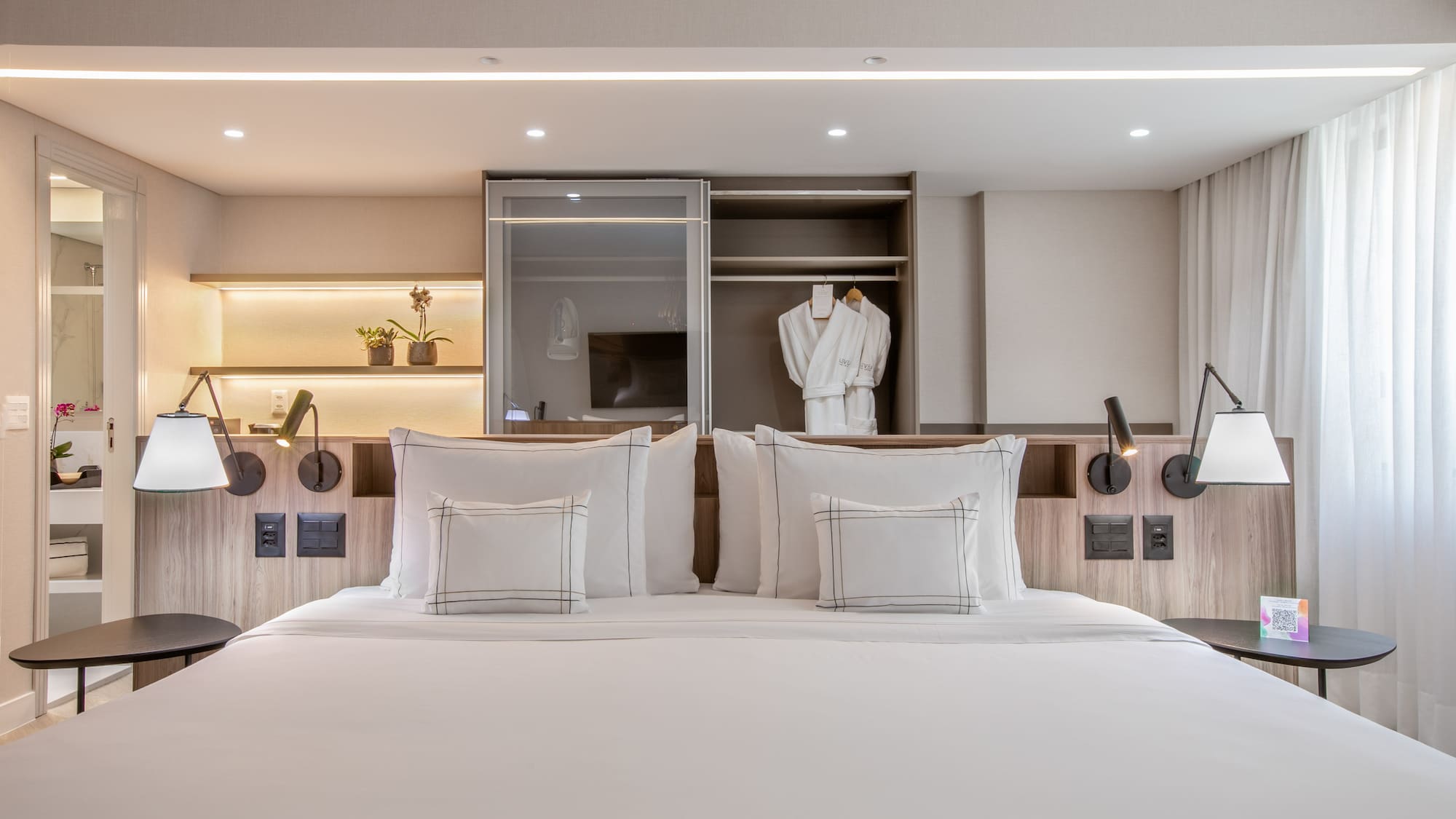 a bed with white pillows and a white robe on the wall